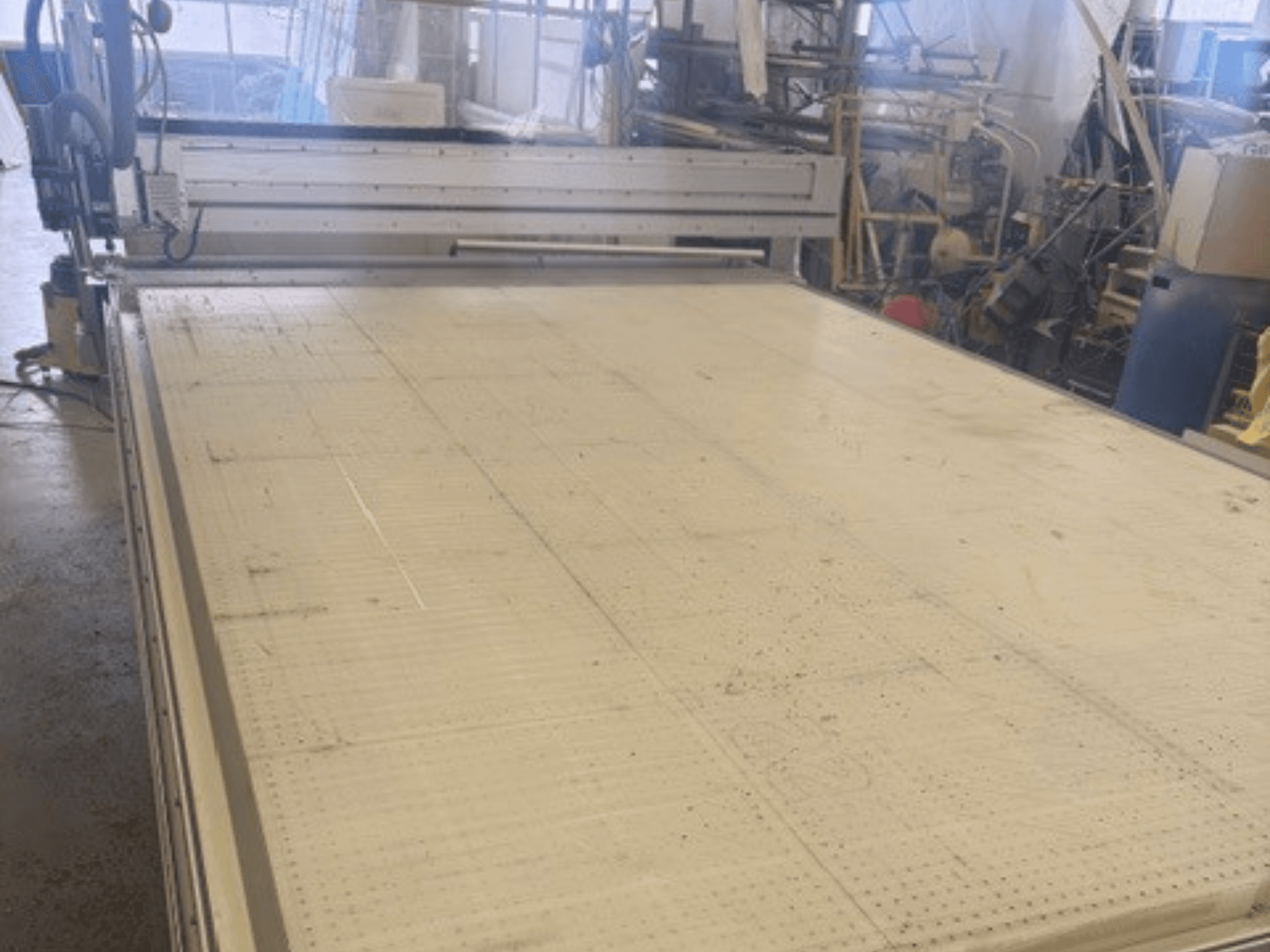 Gran máquina de corte con superficie plana, mostrando el bastidor y el carril guía; vista desde un ángulo en un taller.
