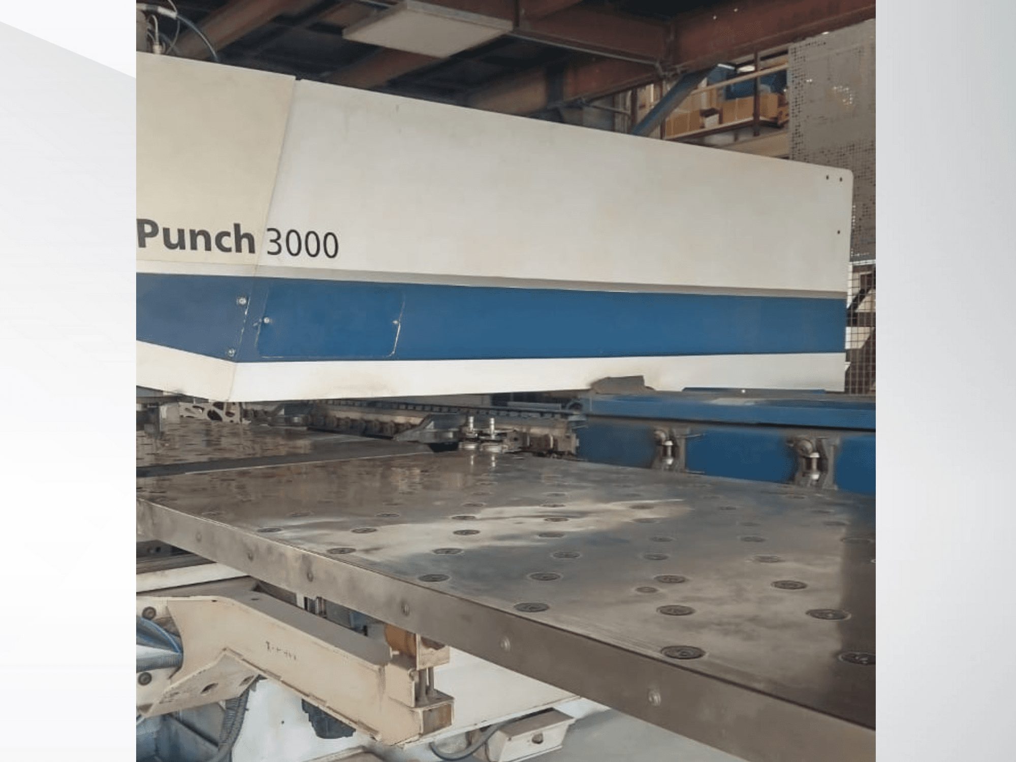 Punzonadora 3000 en un taller, vista frontal, mostrando una gran superficie metálica plana con múltiples orificios de punzonado.