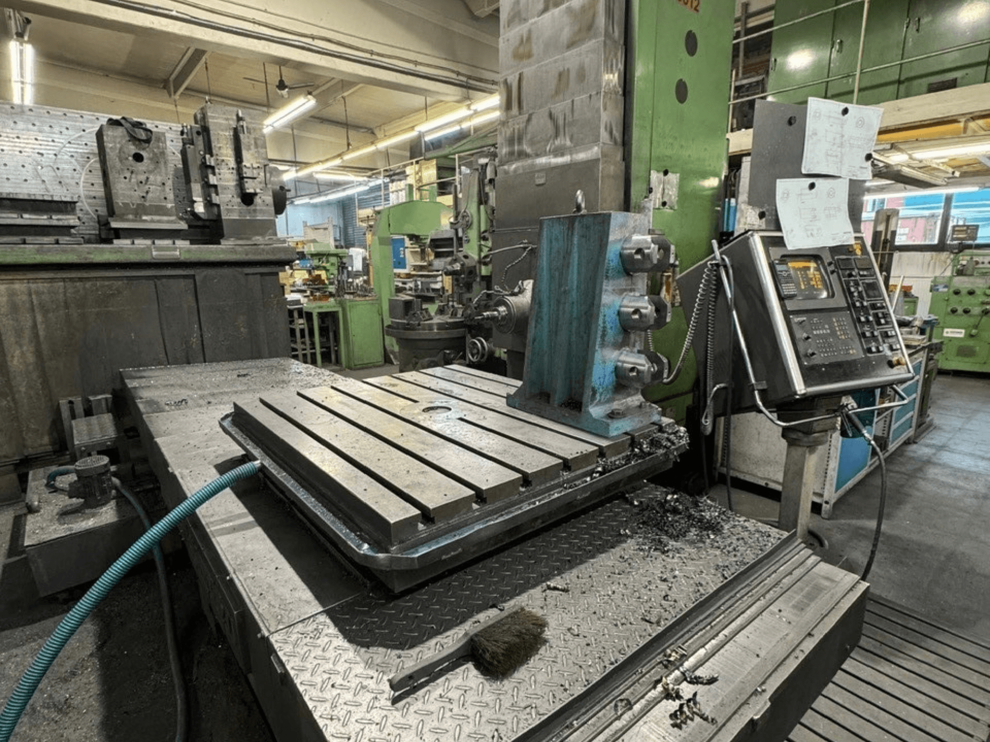 Máquina de mandrinado JUARISTI 12/TS1.7 en un taller; vista lateral en la que se aprecia una mesa metálica con ranuras y el panel de control junto a ella.