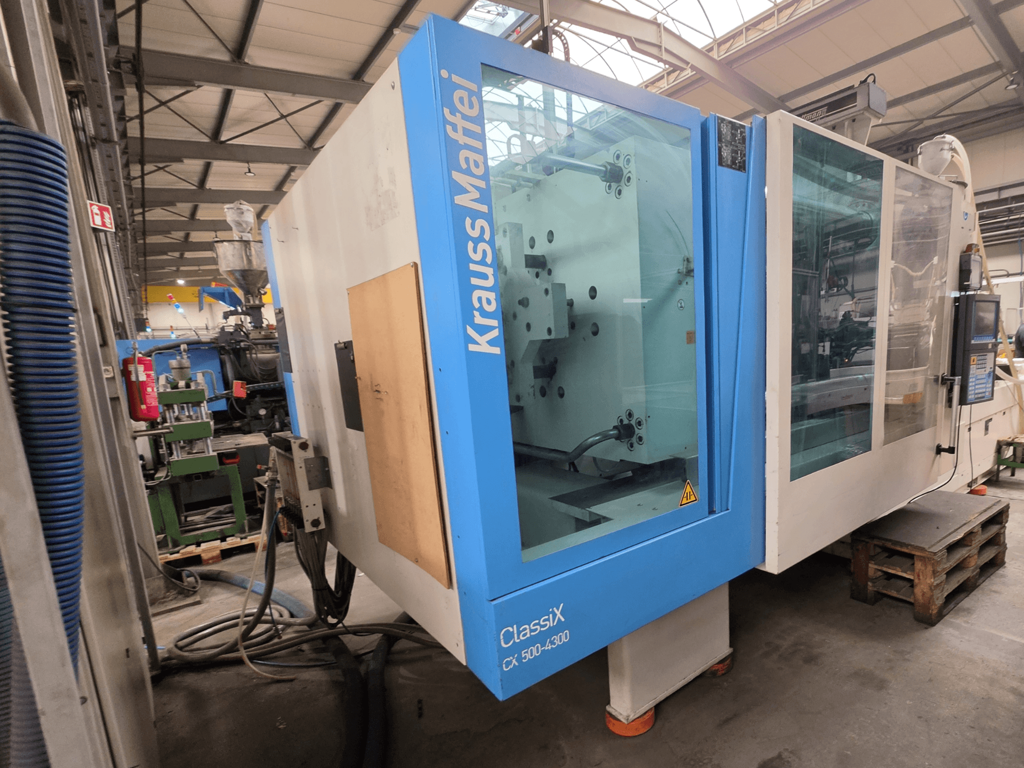 Máquina de moldeo por inyección hidráulica Krauss Maffei 500-4300 CX, vista lateral, mostrando el panel de control y los componentes operativos.