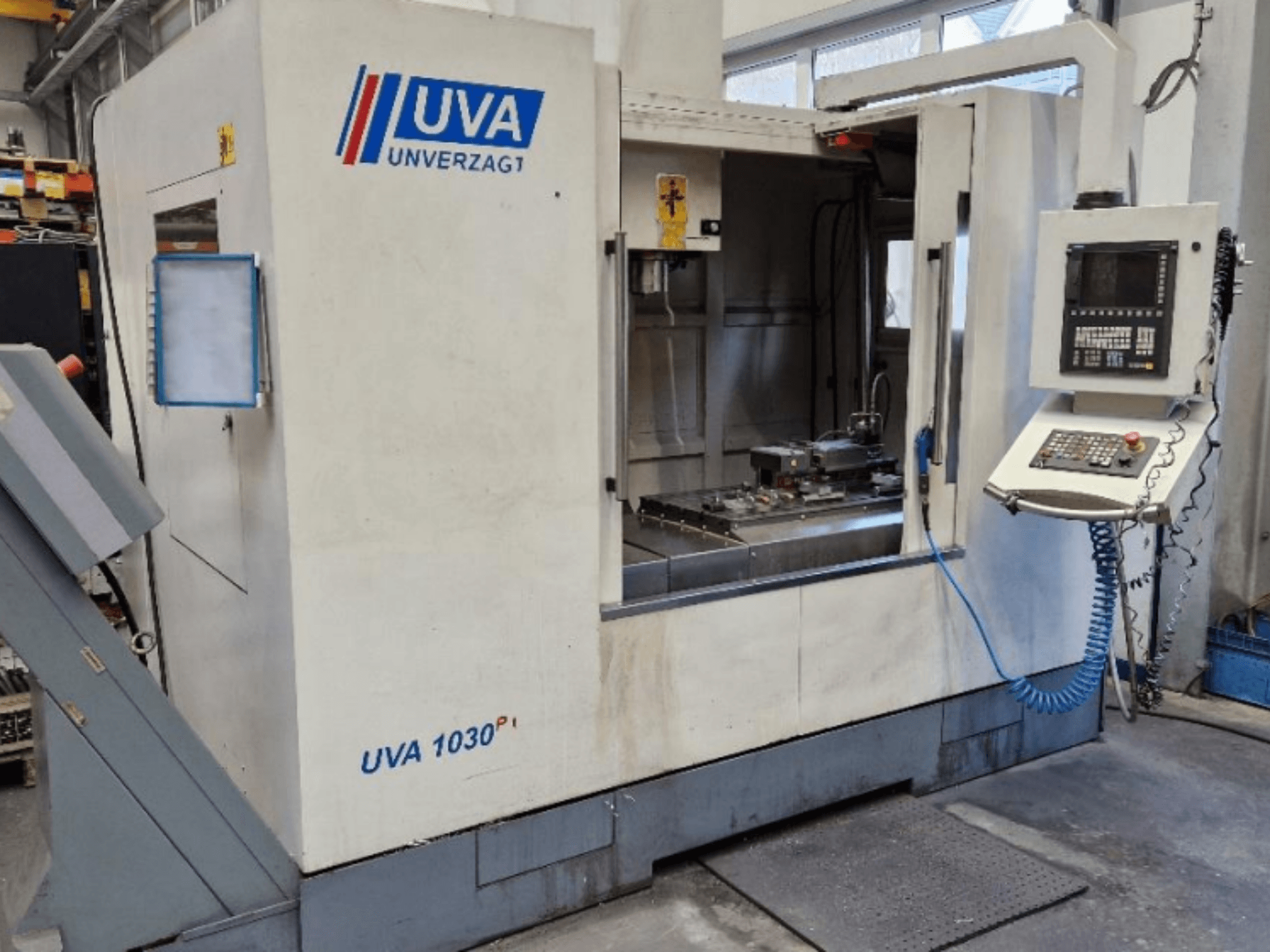 Máquina herramienta UVA 1030P en un taller, vista frontal que muestra el panel de control, el área de trabajo y la superficie de corte limpia.