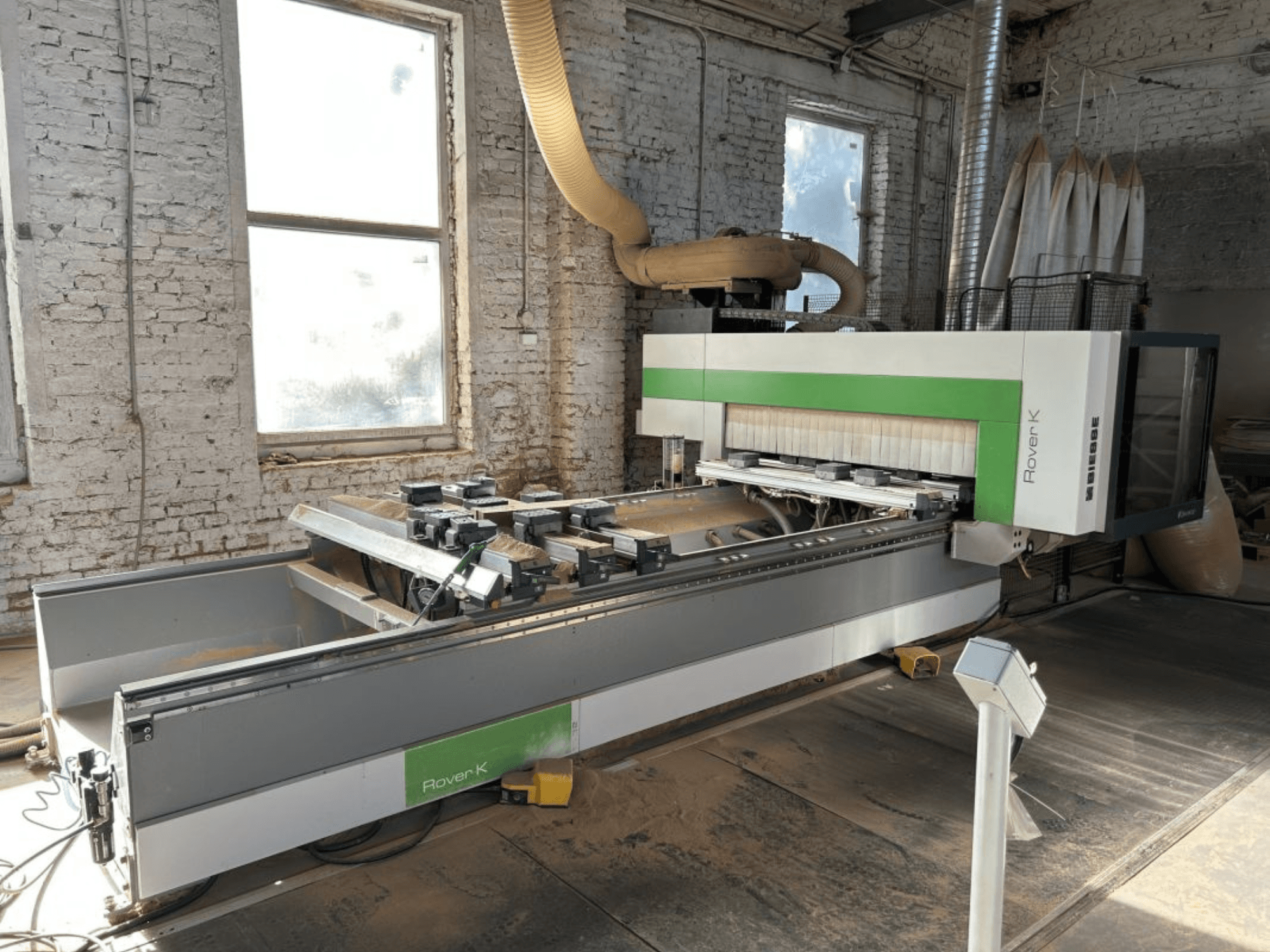 Centro de mecanizado CNC BIESSE Rover K 1532 G en un taller, visto desde delante, mostrando sus herramientas de corte y la superficie de trabajo.