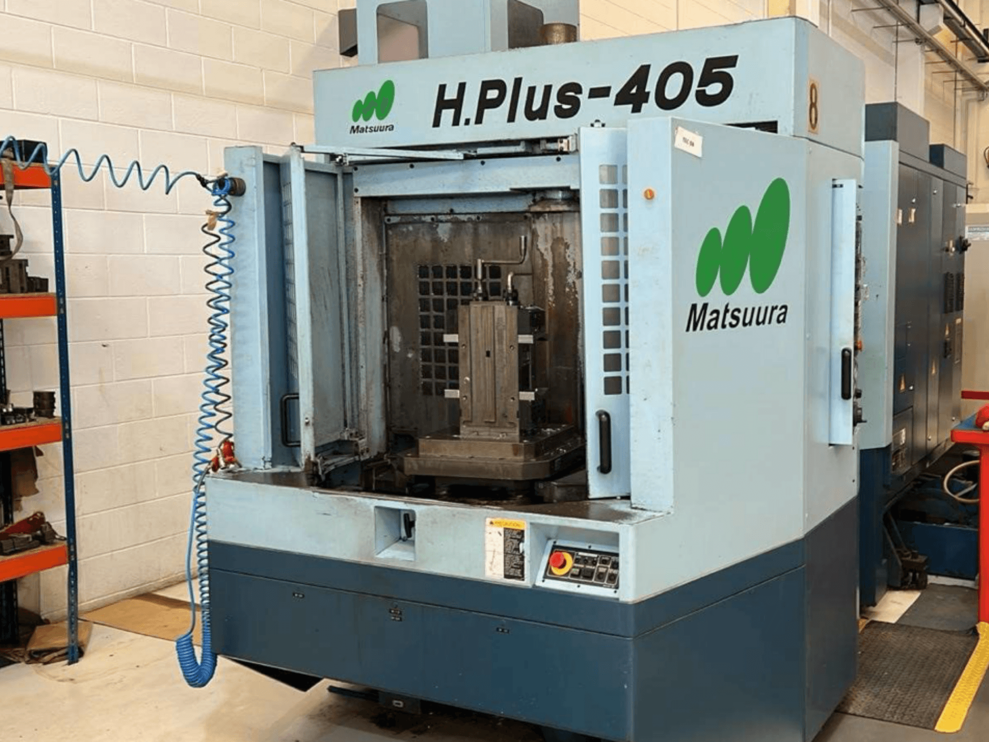 Vista frontal de un centro de mecanizado horizontal Matsuura H.Plus 405 con la puerta abierta, en la que se aprecian el espacio de trabajo y el panel de control.