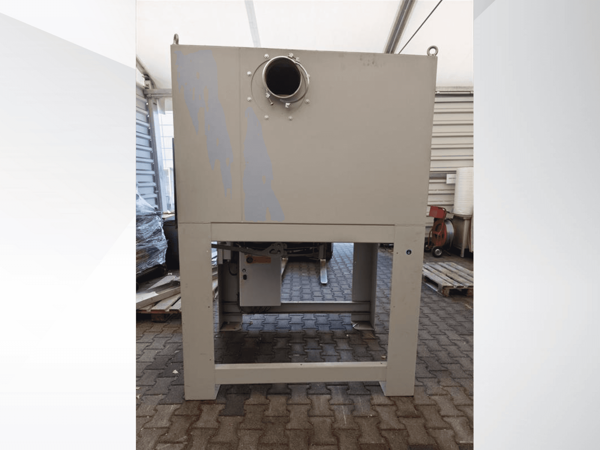 Colector de polvo industrial gris visto de frente, con una gran abertura redonda y montado sobre una base robusta.