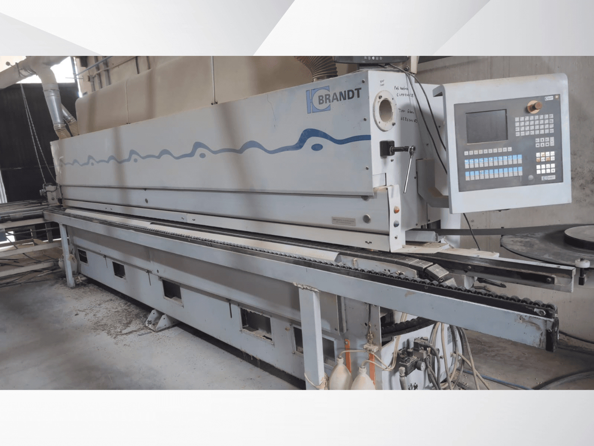 Máquina canteadora BRANDT KDF 560 vista de frente, en la que se aprecian el panel de control y la cinta transportadora de alimentación, con restos de polvo visibles en el suelo.
