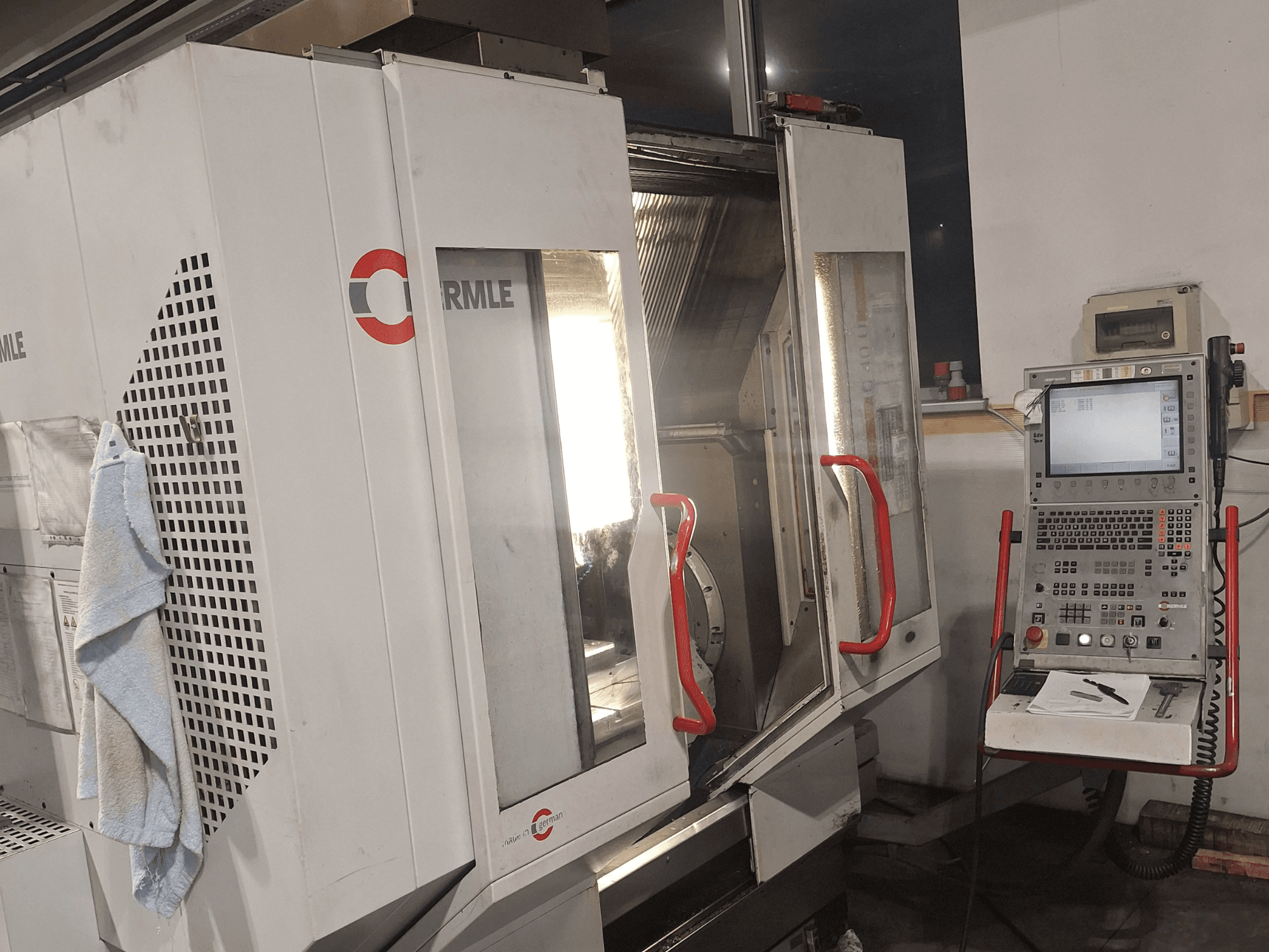 Máquina CNC de la marca Cormile, vista frontal mostrando las puertas parcialmente abiertas y el panel de control con pantalla y botones.