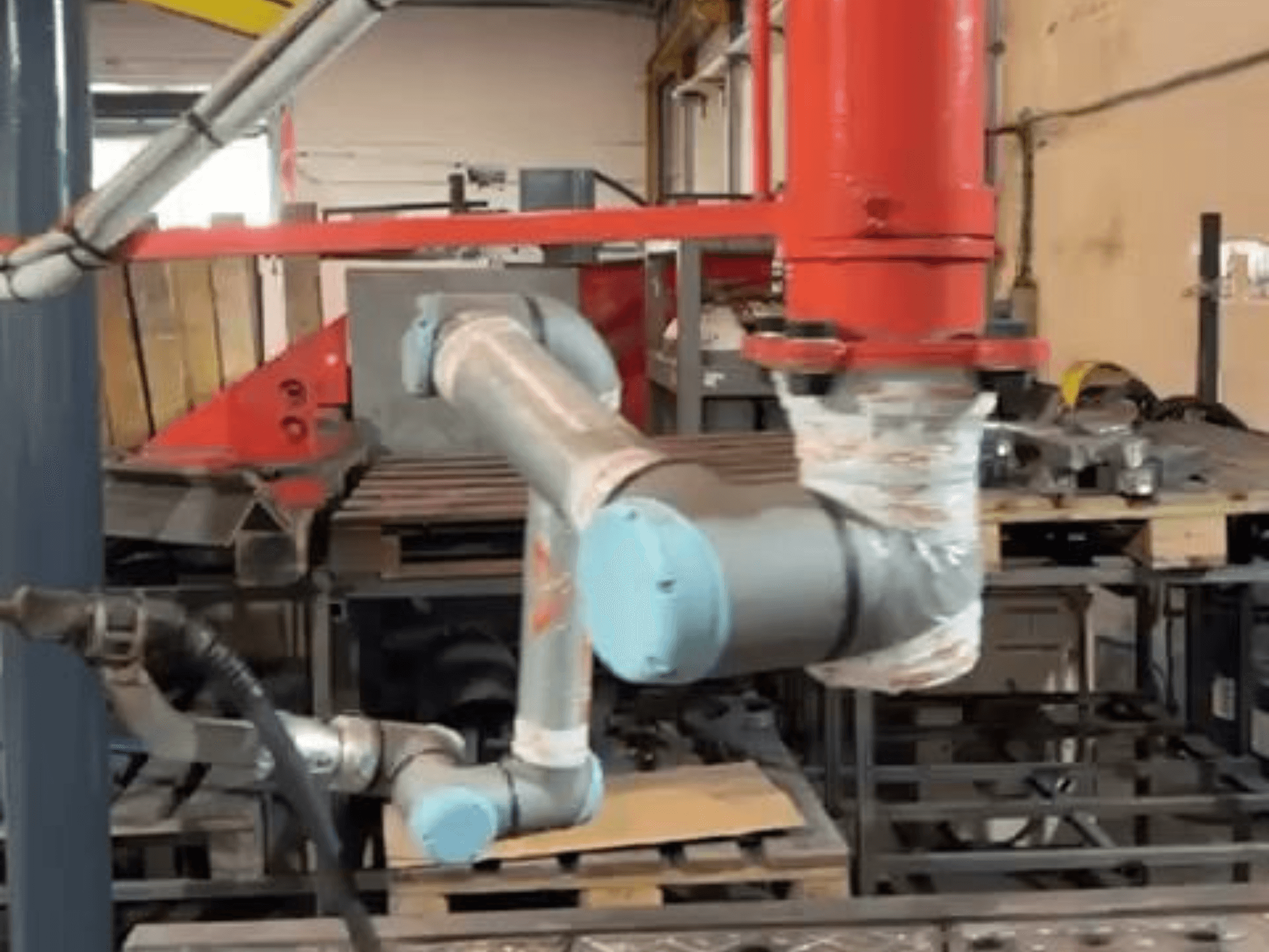 Robot colaborativo UR10e de Universal Robots en un taller; vista lateral que muestra los movimientos del brazo y las articulaciones cerca de la maquinaria.