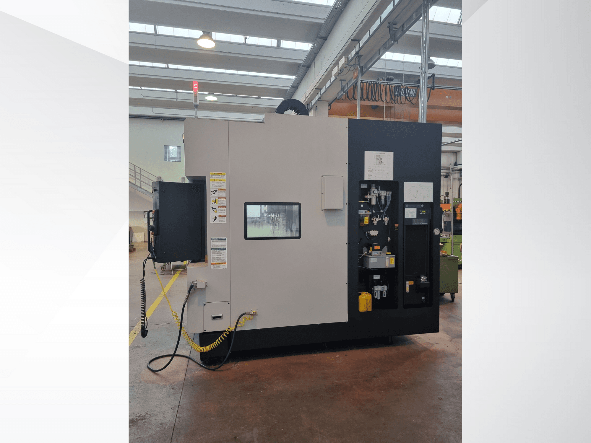 Máquina industrial desde una vista lateral, presenta un panel de control con botones, indicadores y una etiqueta de advertencia de seguridad.