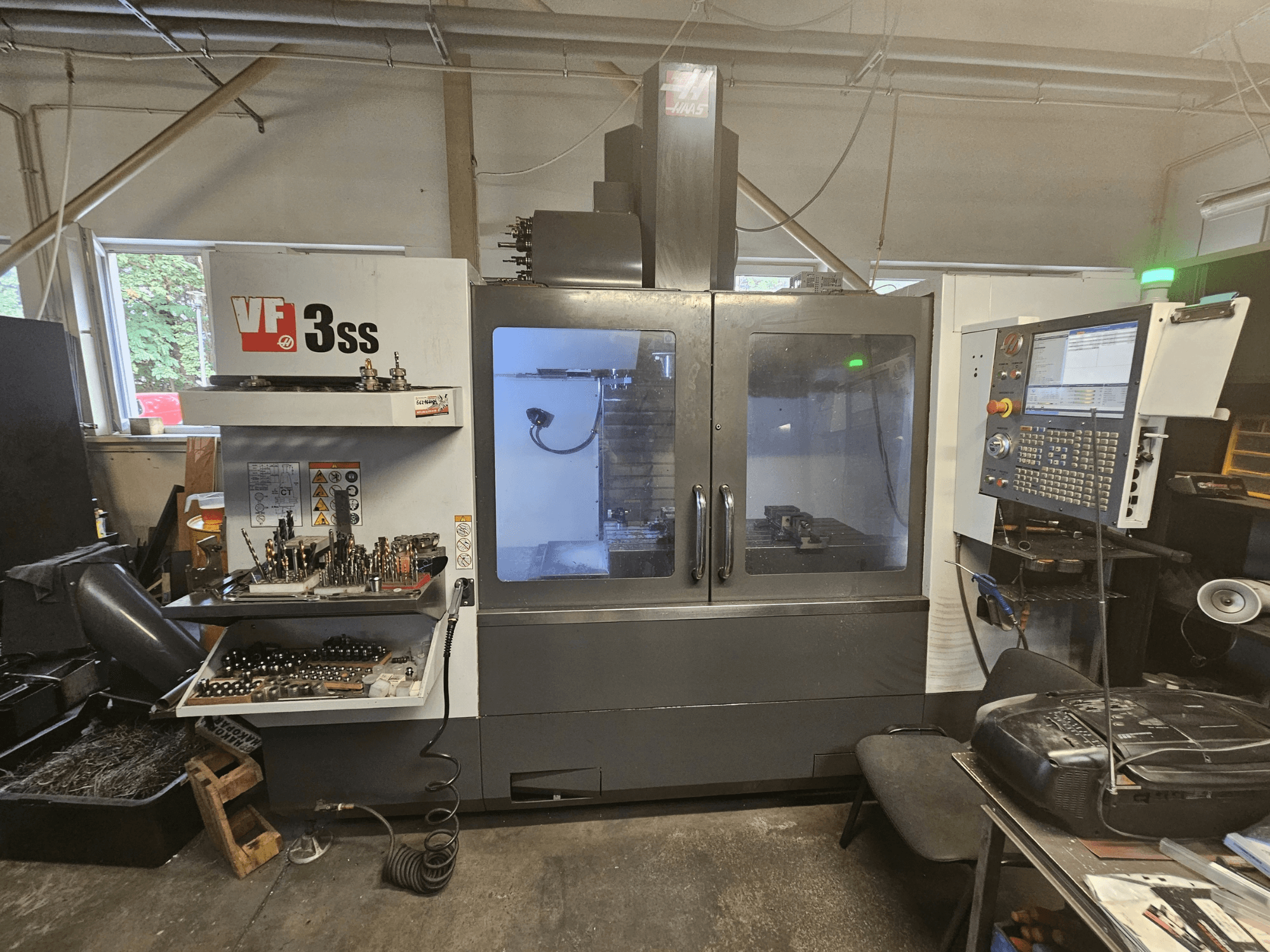 Centro de mecanizado vertical Haas VF-3SS en un taller; vista frontal en la que se aprecian el panel de control y el compartimento de almacenamiento de herramientas.
