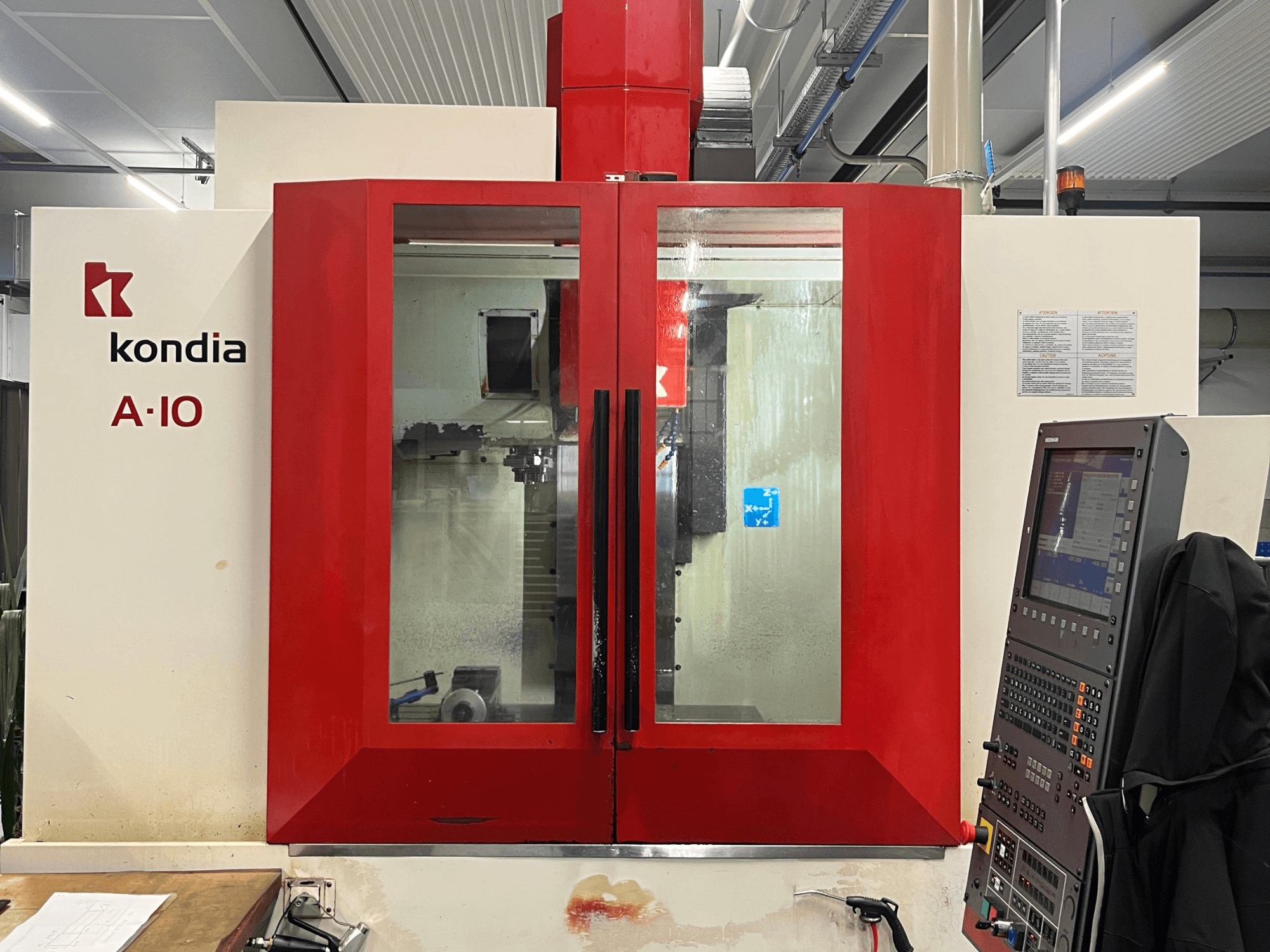 Centro de mecanizado vertical KONDIA A10, vista frontal; presenta puertas de cristal rojo y panel de control a la derecha.