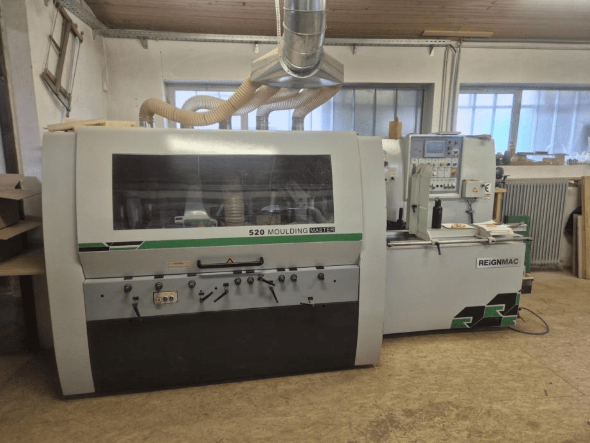 Vista frontal de la cepilladora de madera REIGNMAC 520 MOULDING MASTER, mostrando el panel de control, los rodillos de alimentación y el sistema de extracción de polvo.