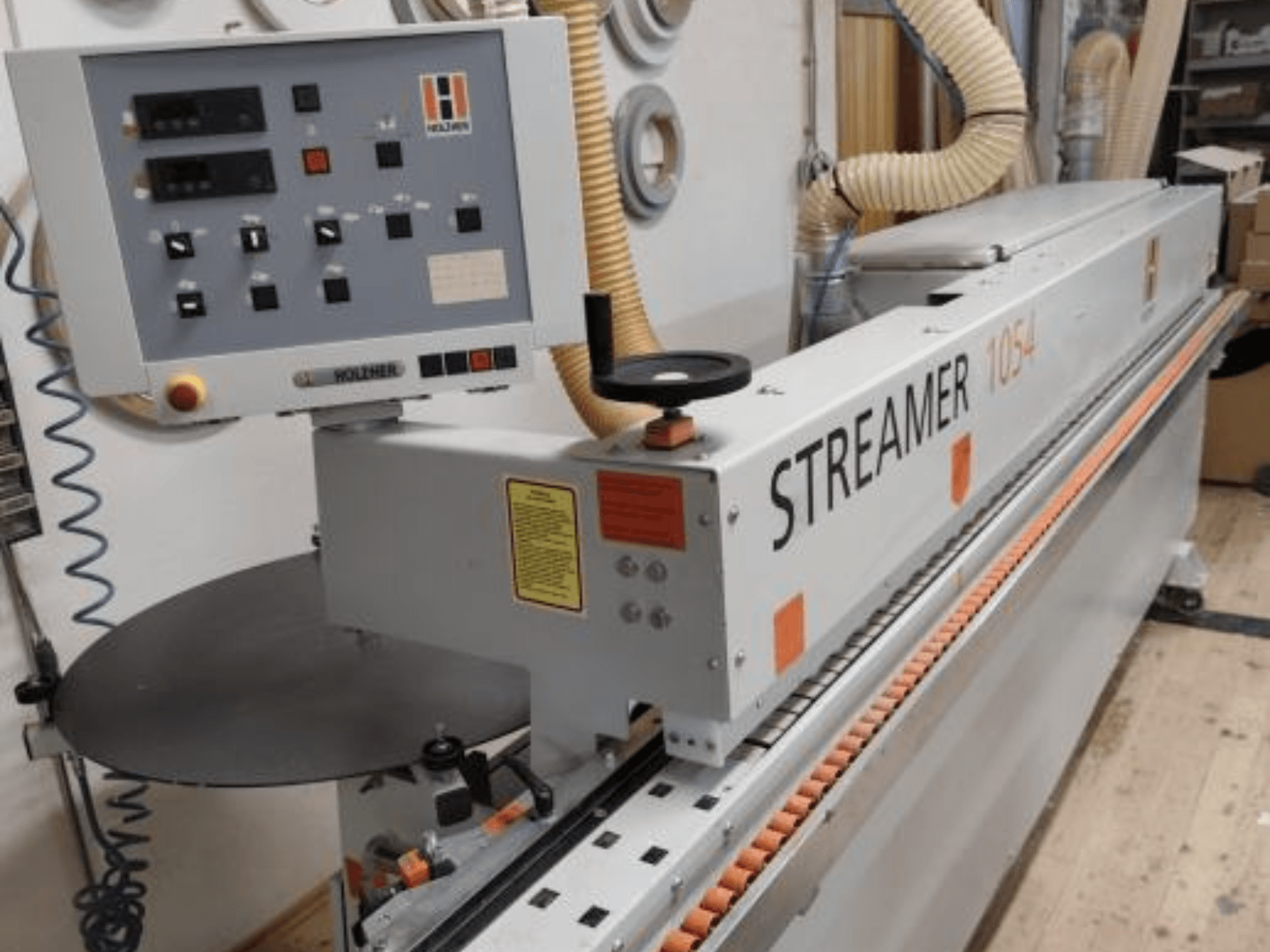 Chapeadora de cantos HOLZHER Streamer 1054, vista lateral mostrando el panel de control y el sistema de alimentación sobre un fondo de taller.
