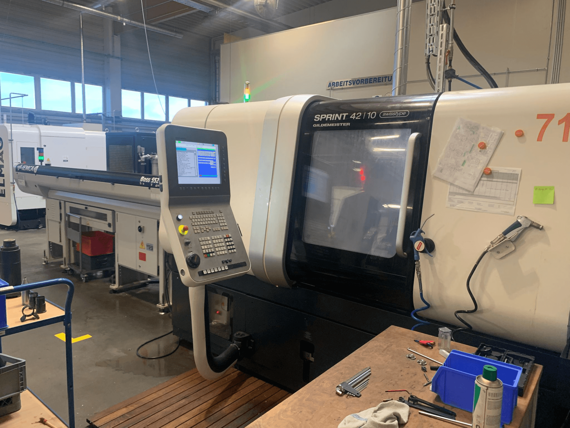 Torneadora lineal DMG MORI Sprint 42/10 de tipo suizo, vista frontal, con panel de control y desorden del espacio de trabajo.