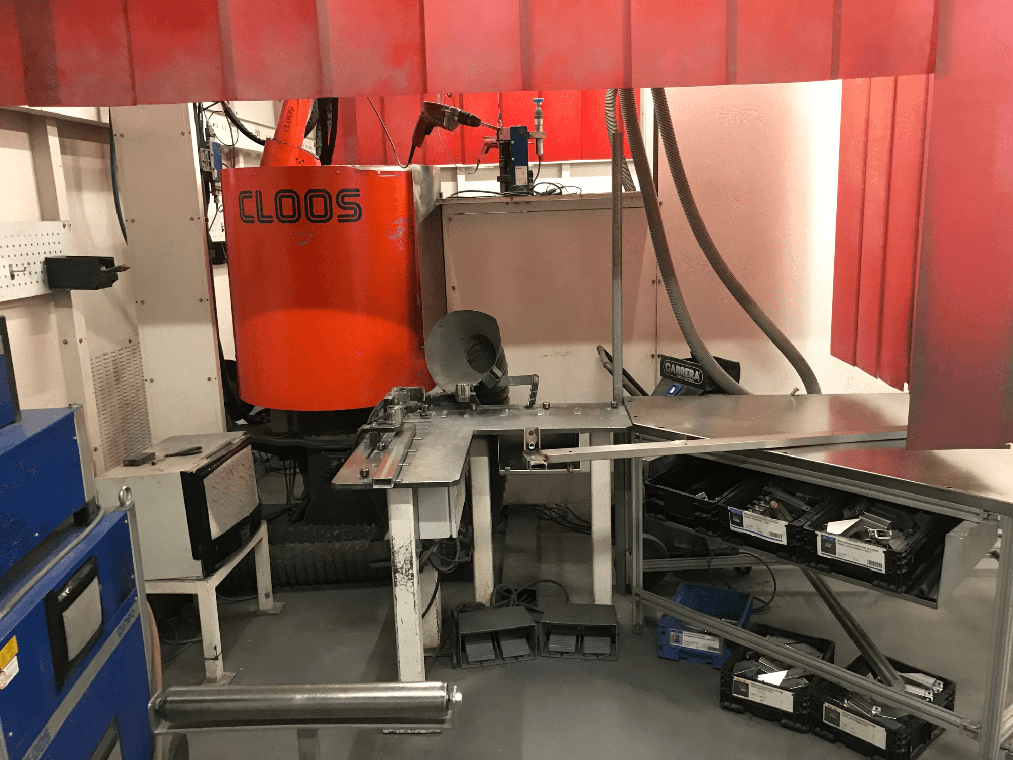 Sistema para talleres de soldadura de DESSAUER; vista frontal en la que se aprecian el brazo robótico, la superficie de trabajo para metalurgia y las zonas de almacenamiento en un entorno de taller.