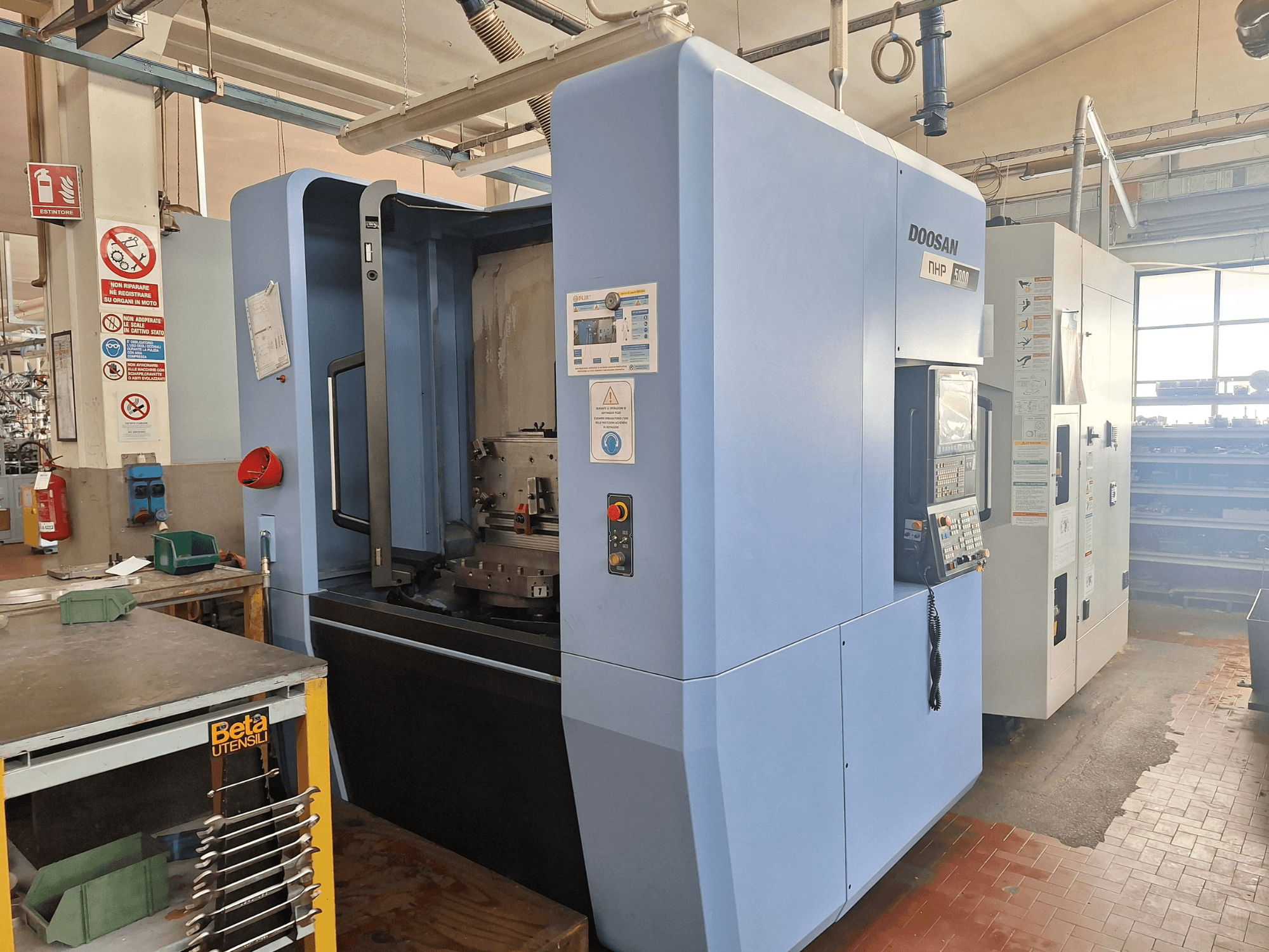 Centro de mecanizado horizontal DOOSAN NHP 5000 en un taller, vista lateral mostrando su panel de control y la zona de mecanizado.