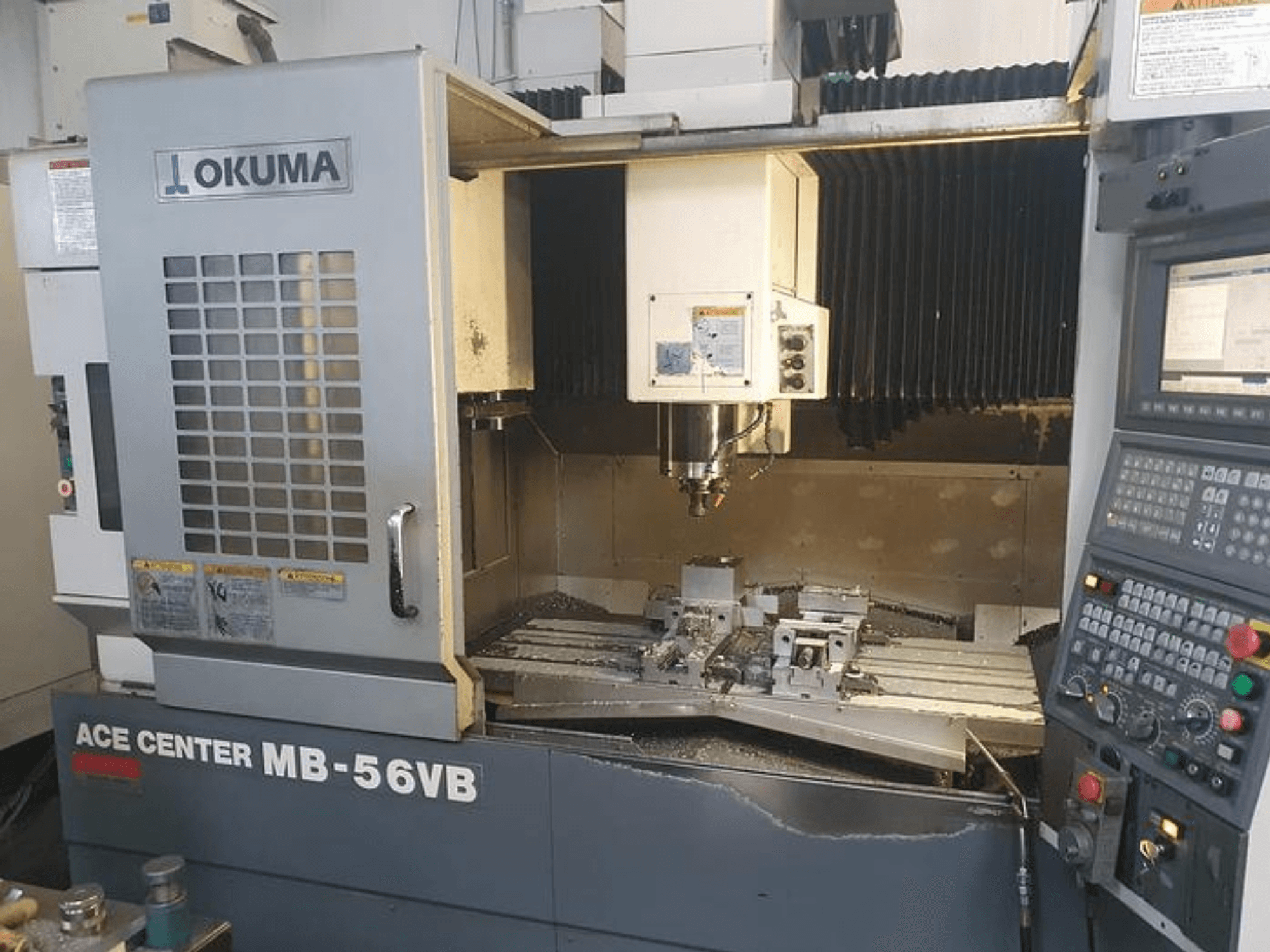 Fresadora CNC Okuma ACE CENTER MB-56VB en una vista frontal, mostrando el panel de control y el área de mecanizado.