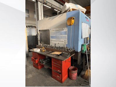 Centro de mecanizado Doosan con un banco de trabajo rojo y almacenamiento, que muestra herramientas y equipos, visto de frente.