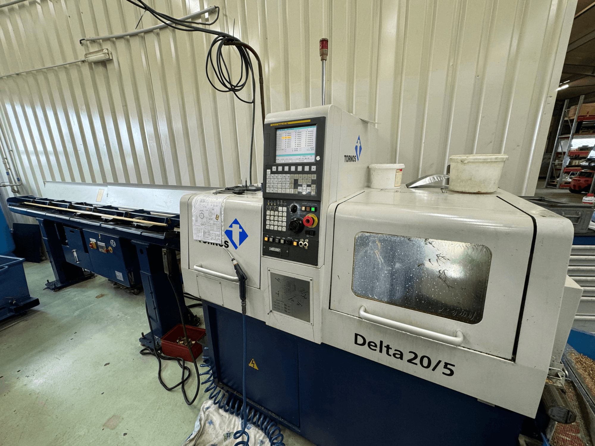 Máquina CNC Torino Delta 20/5, vista frontal, con panel de control y espacio de trabajo. Presenta cristal grabado y cableado visible.