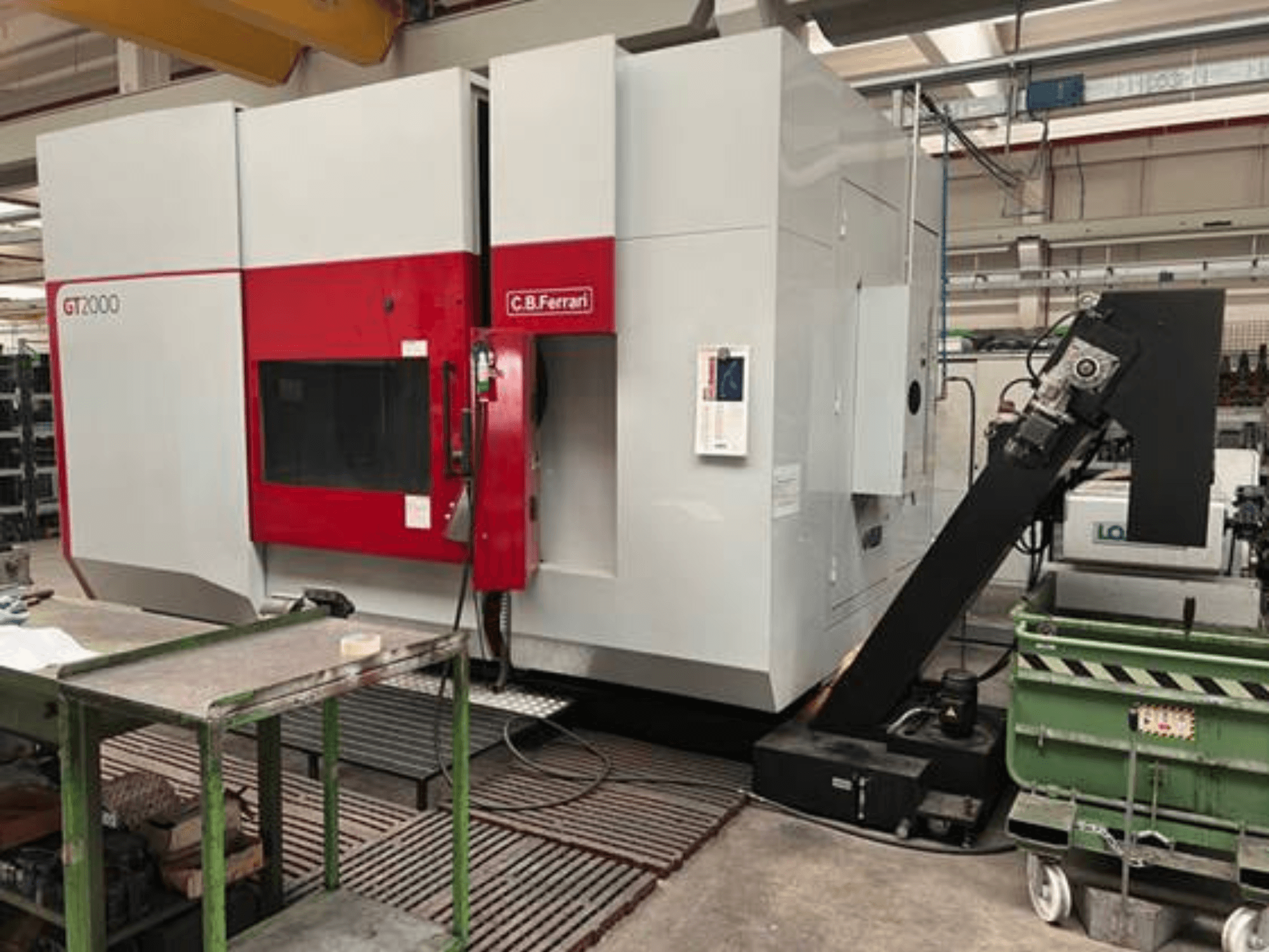Fresadora C.B. Ferrari GT2000 en vista frontal, con brazo robotizado y espacio de trabajo industrial con carro verde.