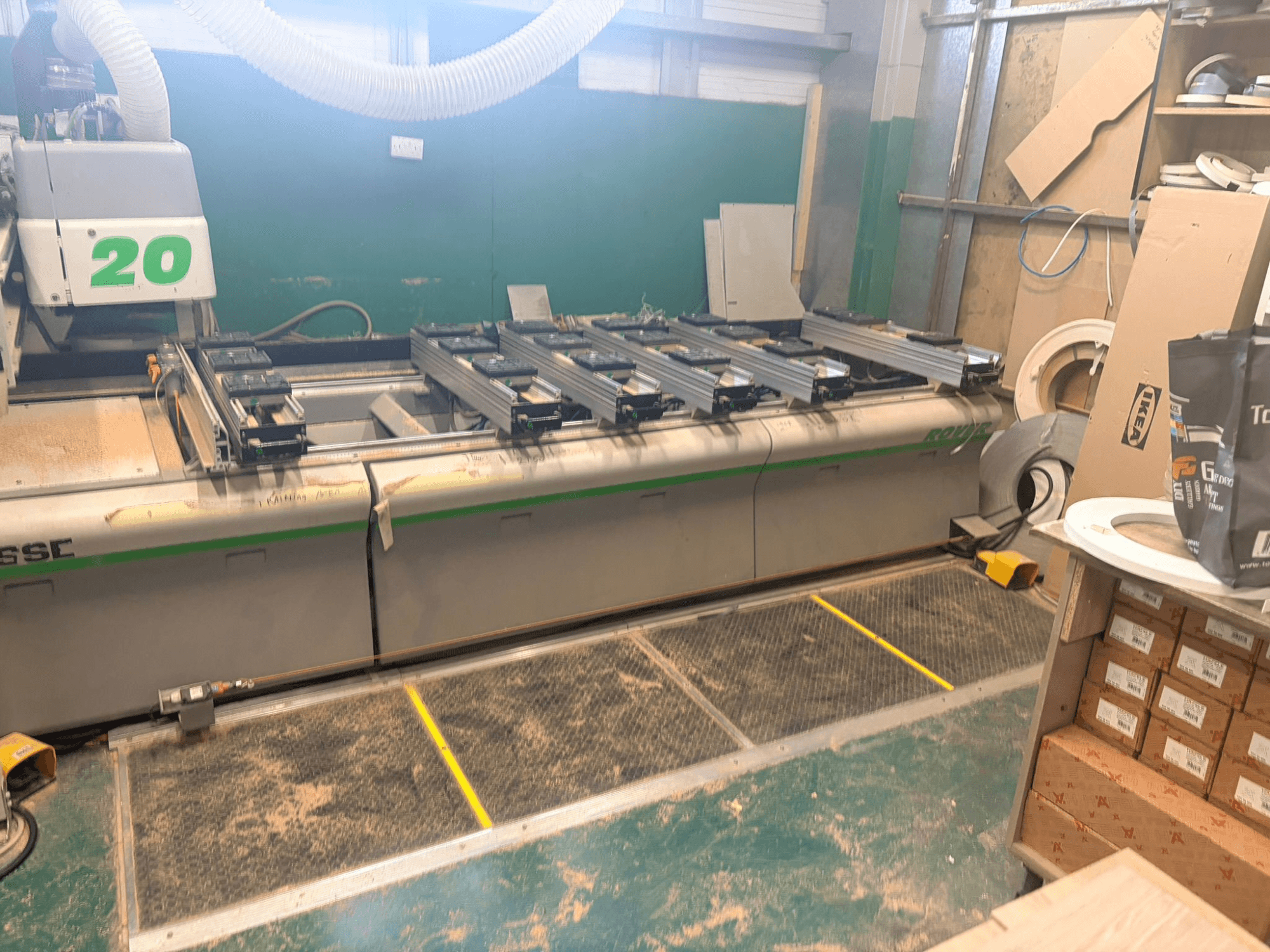 Centro de mecanizado de madera CNC BIESSE ROVER 20, vista frontal, con sistema de raíles, controles y serrín visible en la superficie.