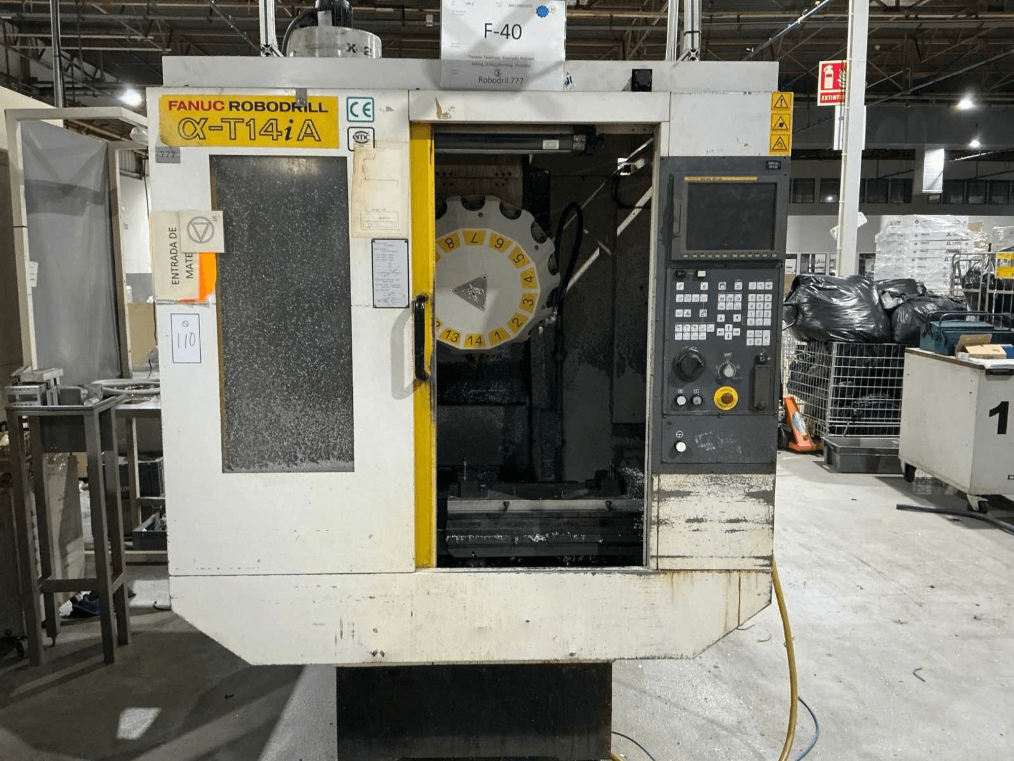 Centro de mecanizado vertical FANUC ROBODRILL α-T14iB, vista frontal mostrando panel de control y carrusel de herramientas.