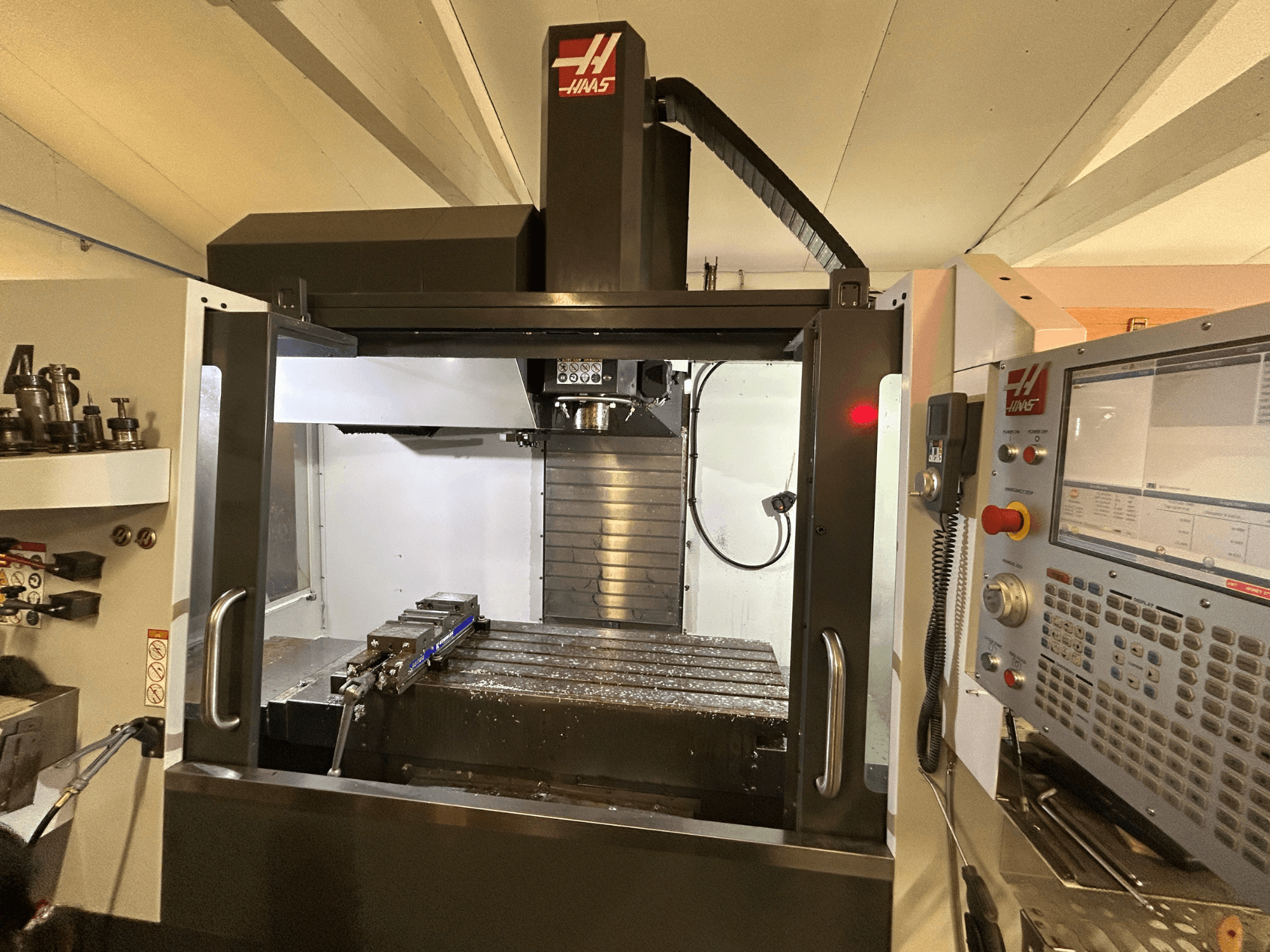 Centro de mecanizado vertical HAAS VF-4SS, vista frontal, mostrando el panel de control, el portaherramientas y la zona de trabajo con virutas de metal.