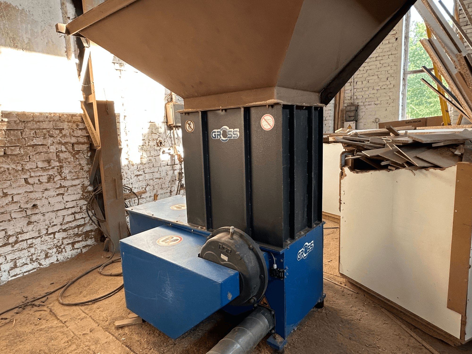 Máquina para el procesamiento de madera GROSS GAZ62 en un taller, con una tolva vertical y dos unidades de base azules, vista desde un lateral.