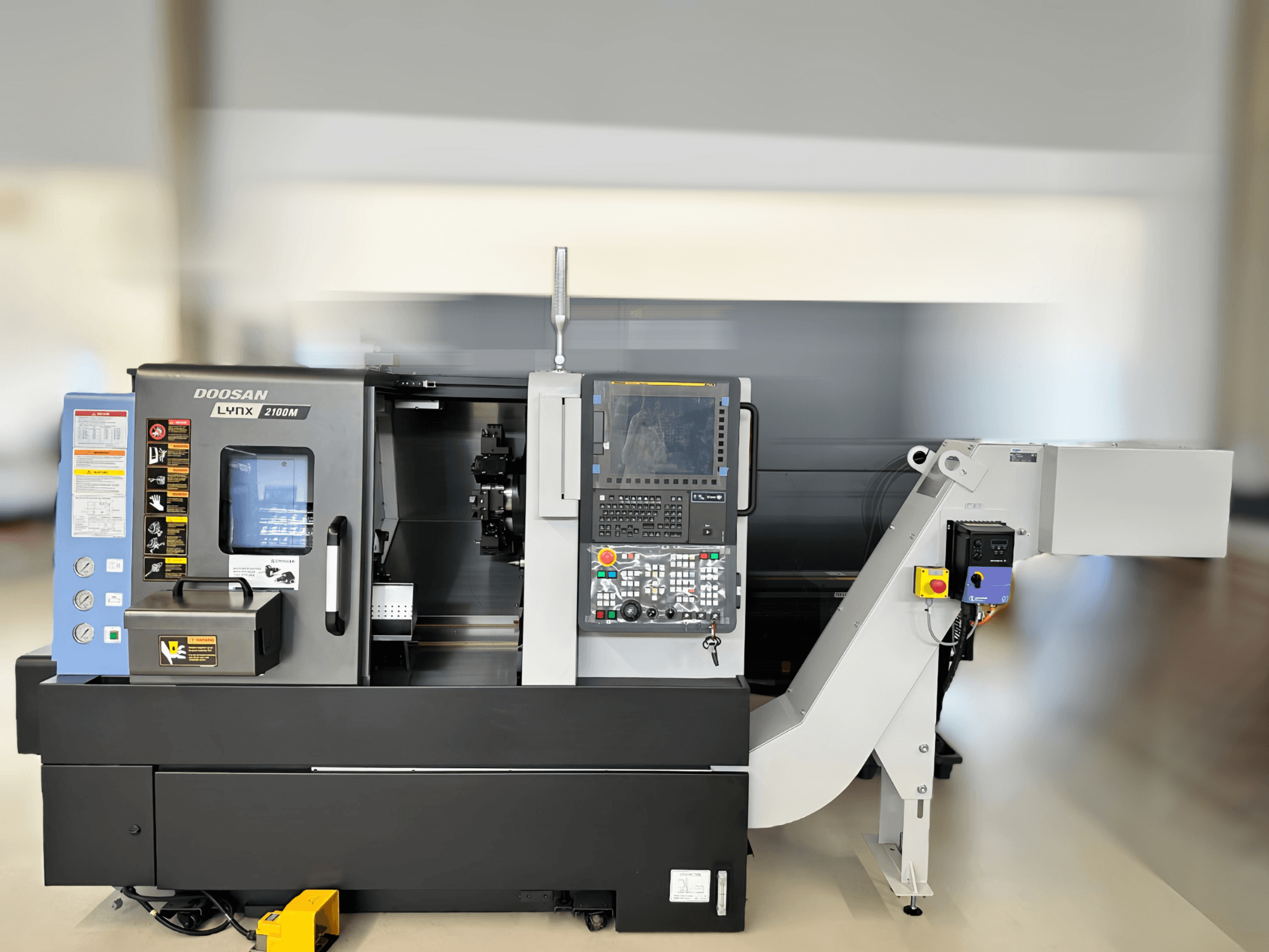 Vista frontal del torno horizontal DN SOLUTIONS LYNX 2100MB, mostrando el panel de control y los detalles del área de trabajo.