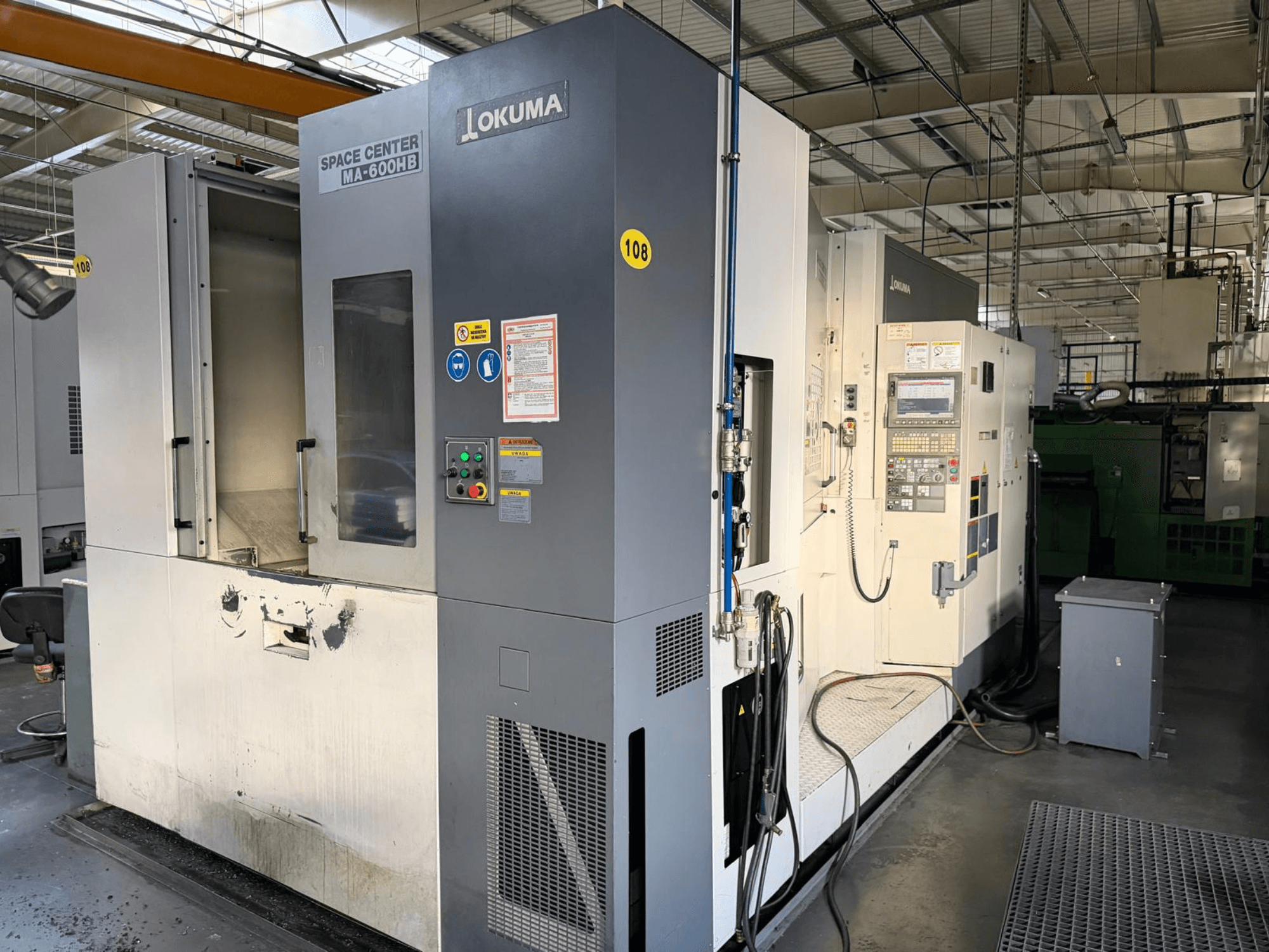 Centro de mecanizado horizontal Okuma MA-600 HB, vista frontal, mostrando el panel de control y la zona de corte con marcas de desgaste visibles.