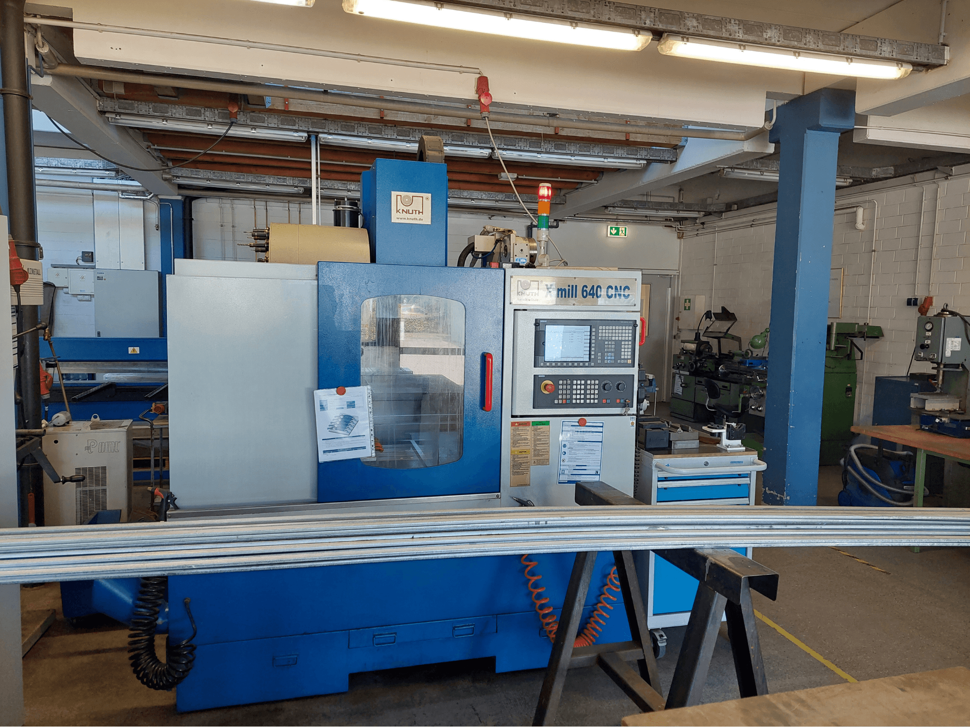 Centro de mecanizado vertical KNUTH X-Mill 640, vista frontal, con el panel de control y la superficie de trabajo en un entorno de taller.