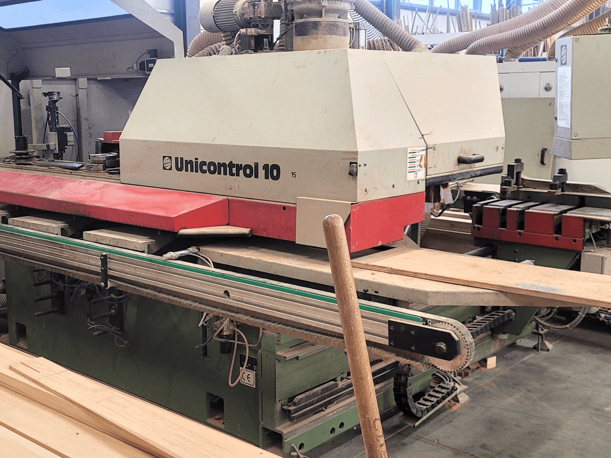 Centro de procesamiento CNC Unicontrol 10 de WEINIG/DIMTER, vista frontal con tableros de madera y equipos en un entorno de taller.
