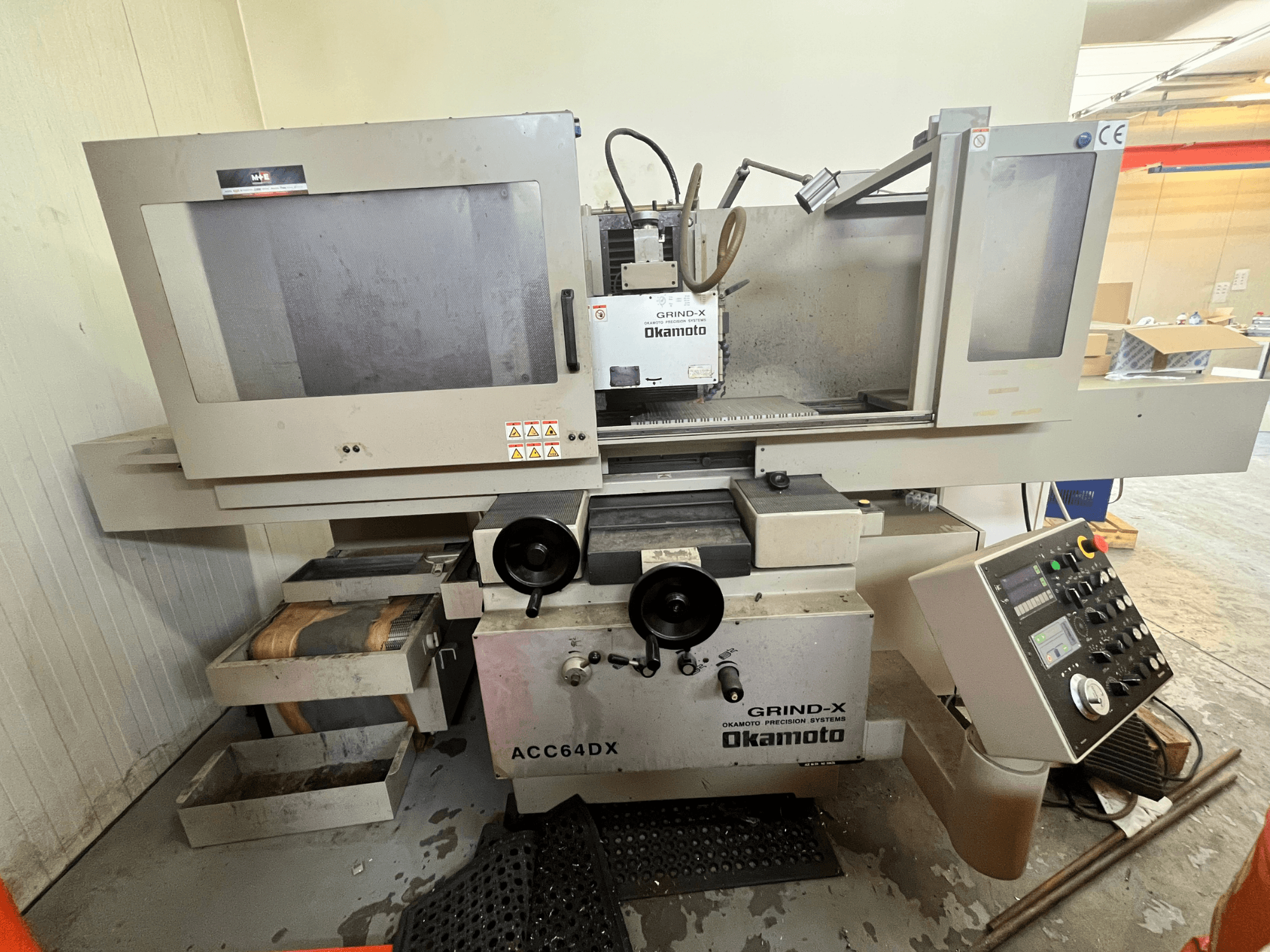 Máquina rectificadora plana Okamoto ACC64 DX vista de frente, en la que se aprecian la muela, el panel de control y los cajones de almacenamiento.