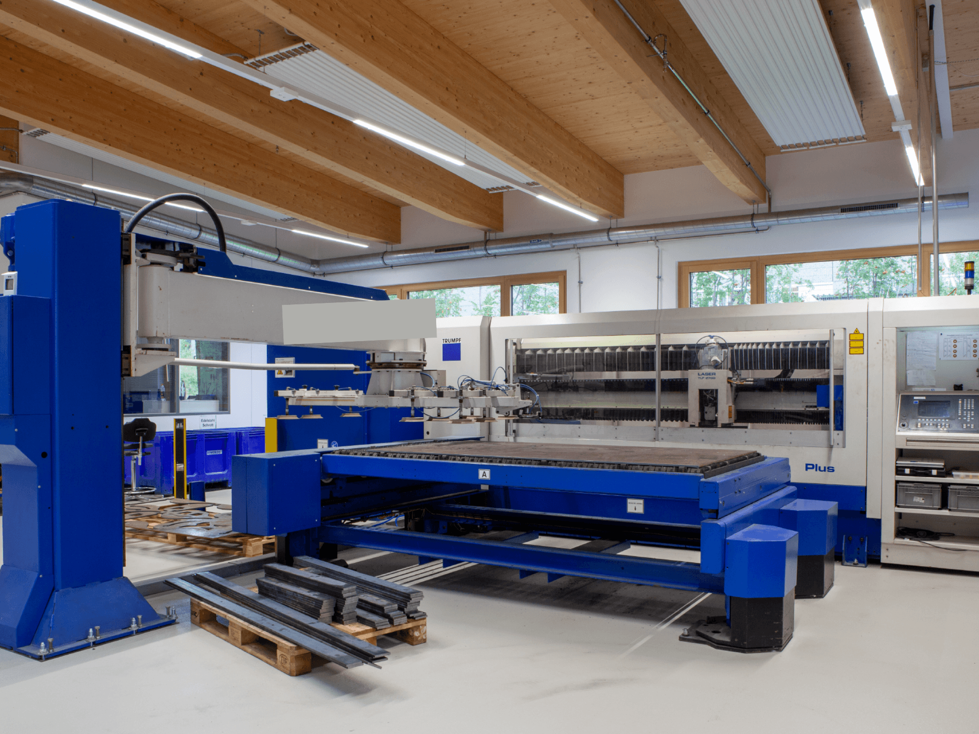 Máquina de corte por láser de CO₂ TRUMPF TRUMATIC L 2530 Plus en un taller, que destaca por su amplia mesa de corte y su diseño industrial.