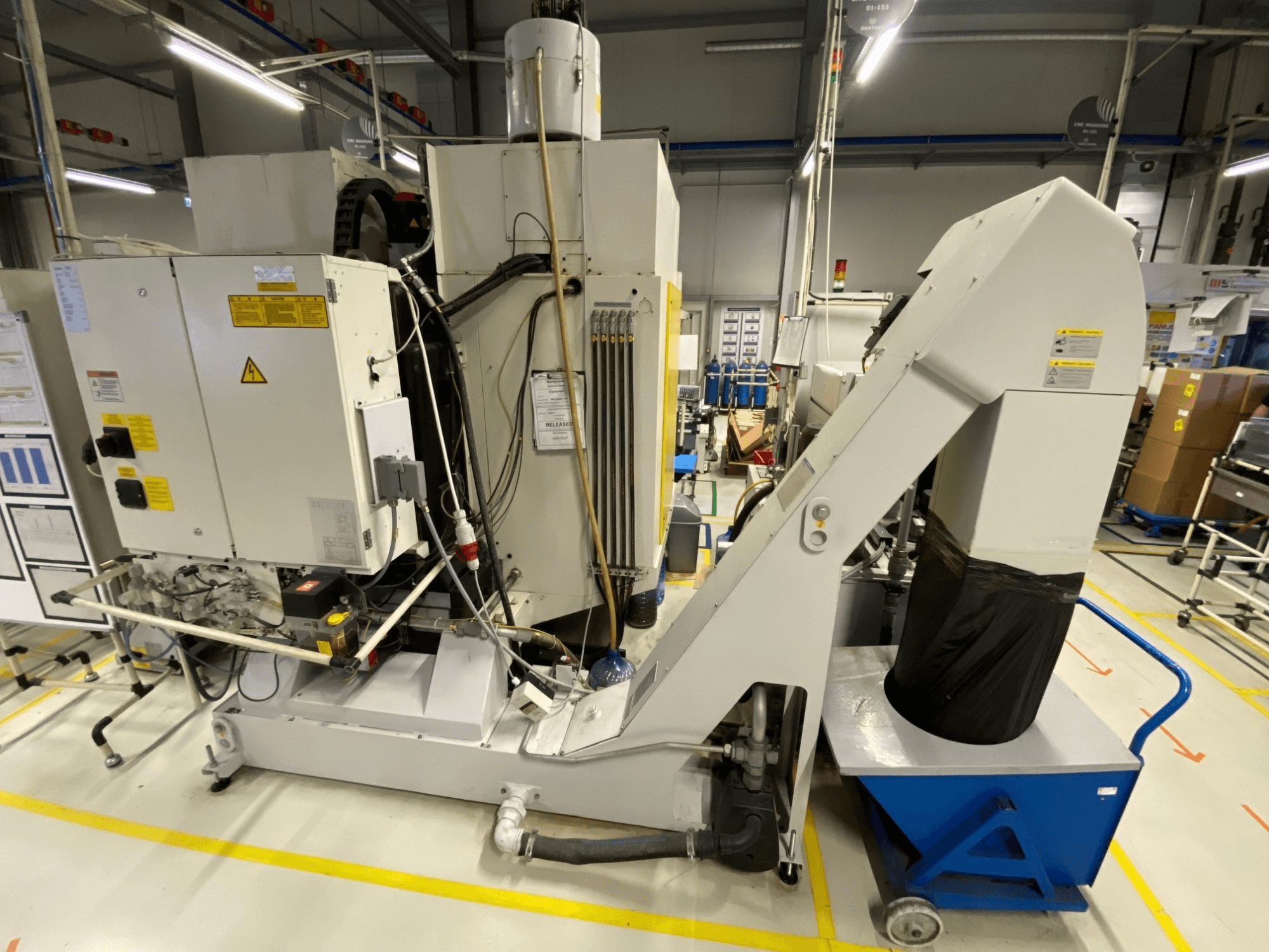 Vista frontal del centro de mecanizado vertical FANUC ROBODRILL α-D21LiB, en la que se aprecian los componentes eléctricos y la rampa de salida.