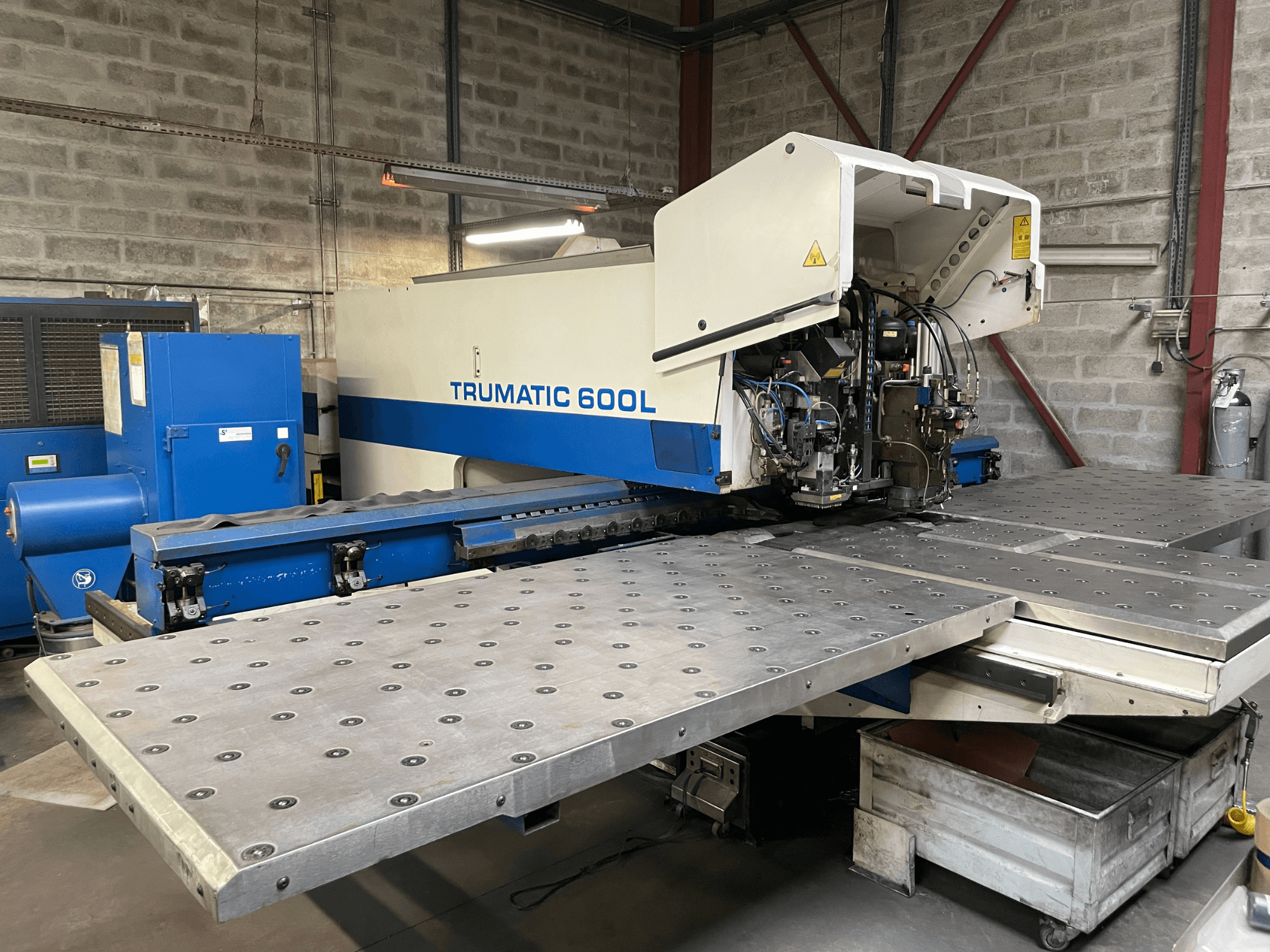 Máquina de corte por láser CO2 TRUMPF TRUMATIC TC 600L, vista frontal con mesa de corte de metal y panel de control visibles.