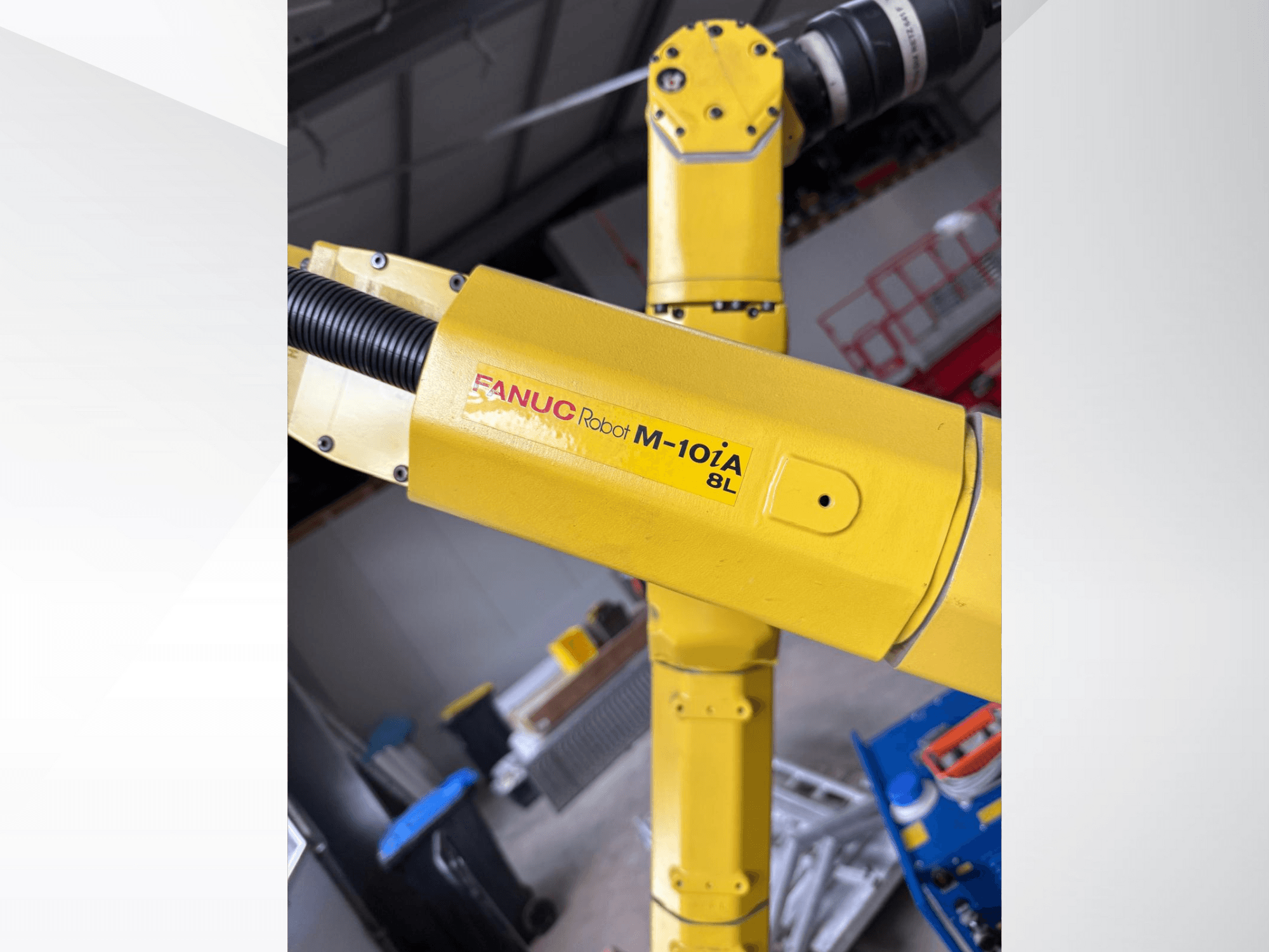 Robot FANUC M-10iA 8L en amarillo, visto de lado, mostrando la articulación del brazo y los componentes mecánicos en un entorno industrial.