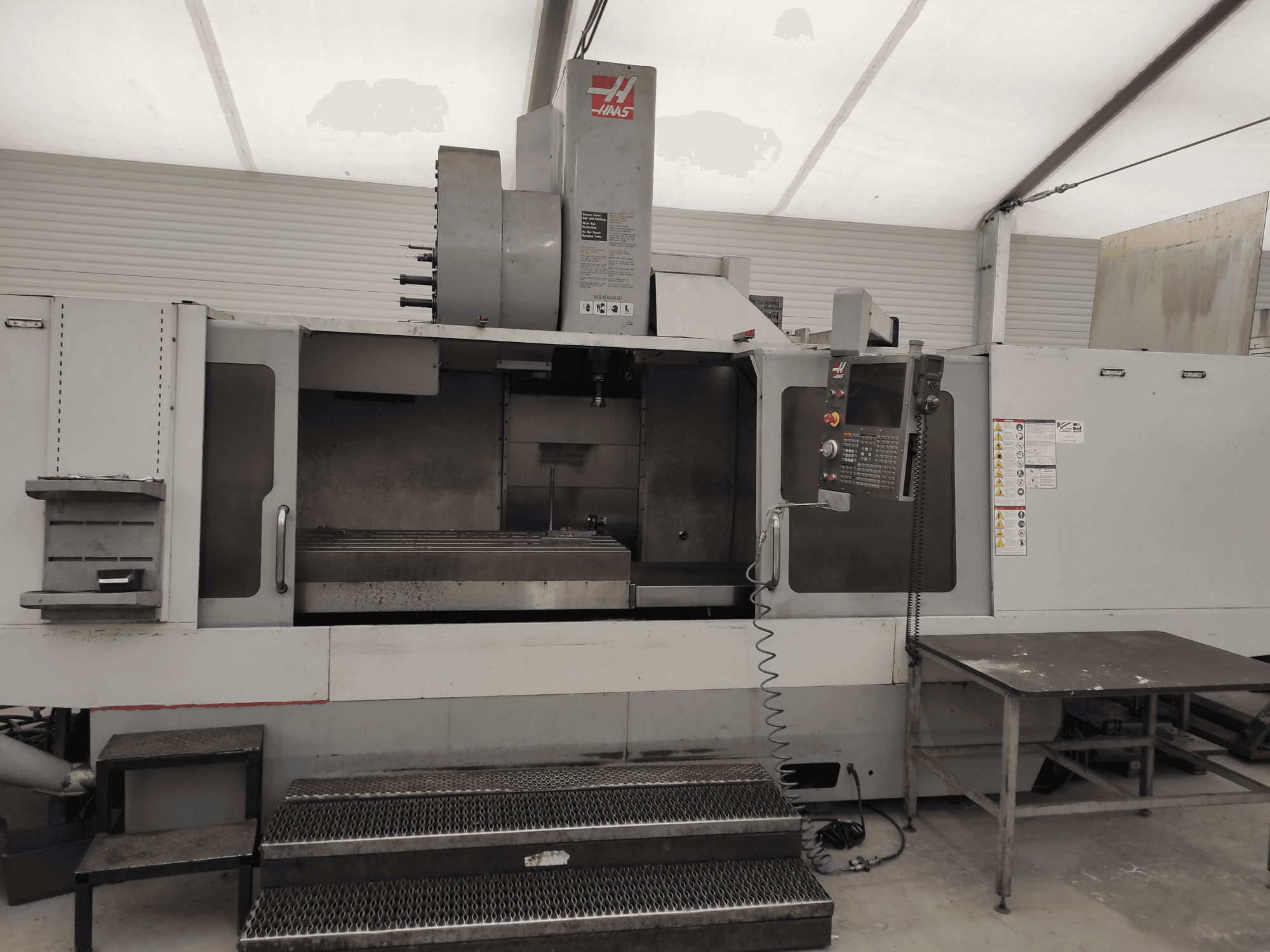 Centro de mecanizado vertical HAAS VF-10/50HE, vista frontal mostrando el panel de control, la bancada de la máquina y el escalón accesible para su manejo.