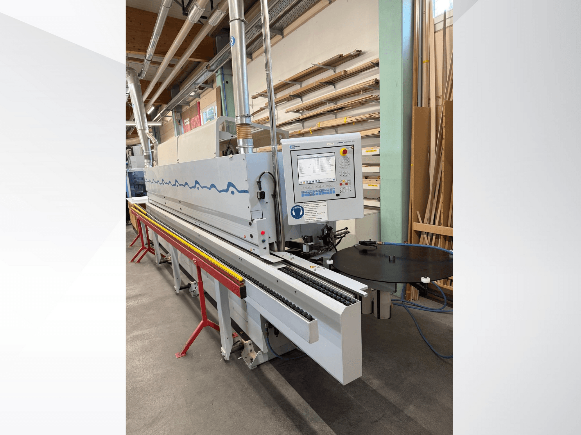 Vista frontal de una encoladora de cantos automática HolzHer con panel de control, sistema de transporte y mesa de apoyo redonda.