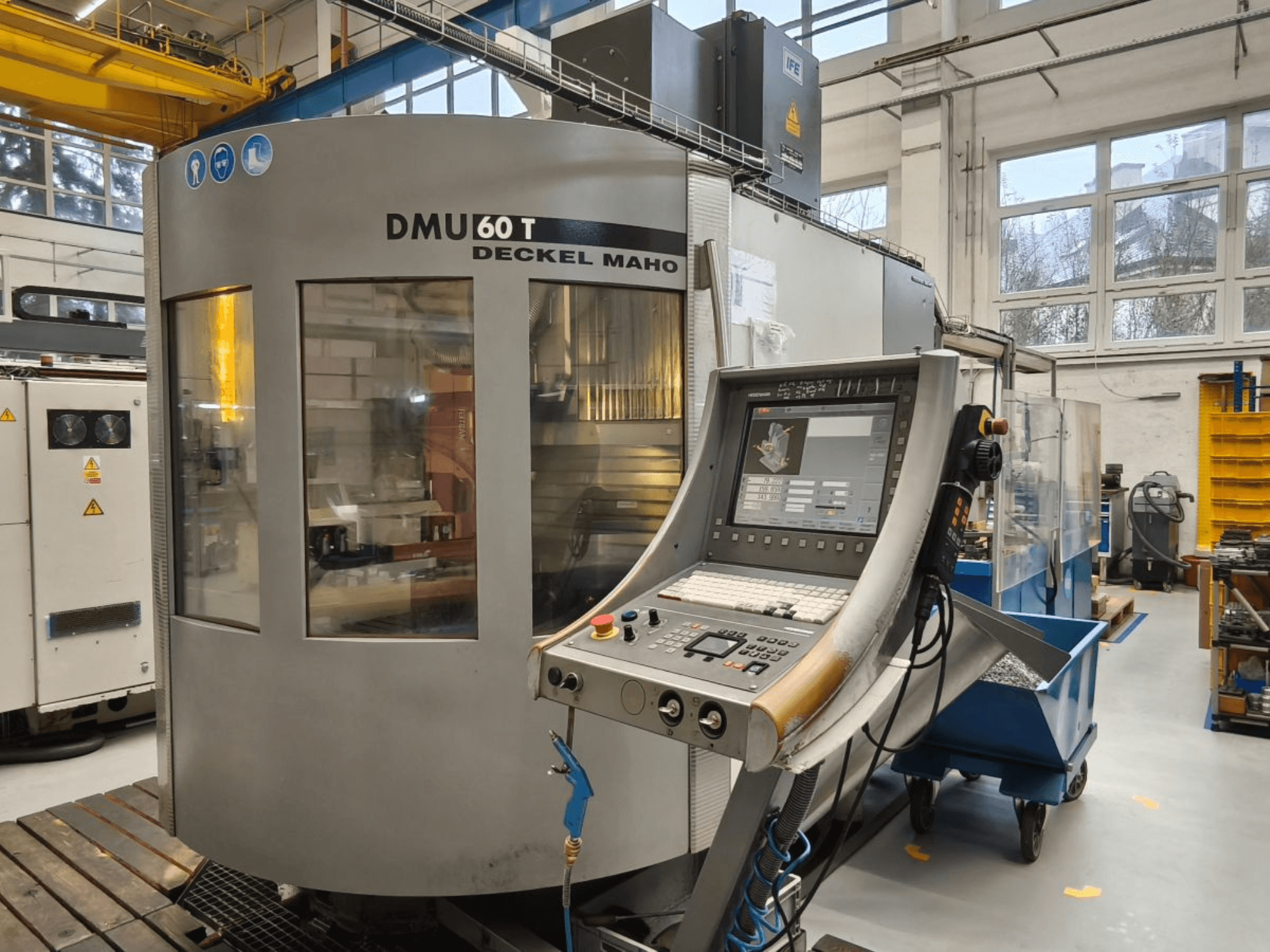 Vista vertical del centro de mecanizado DECKEL MAHO DMU 60T con panel de control, mostrando herramientas de precisión dentro de un taller.