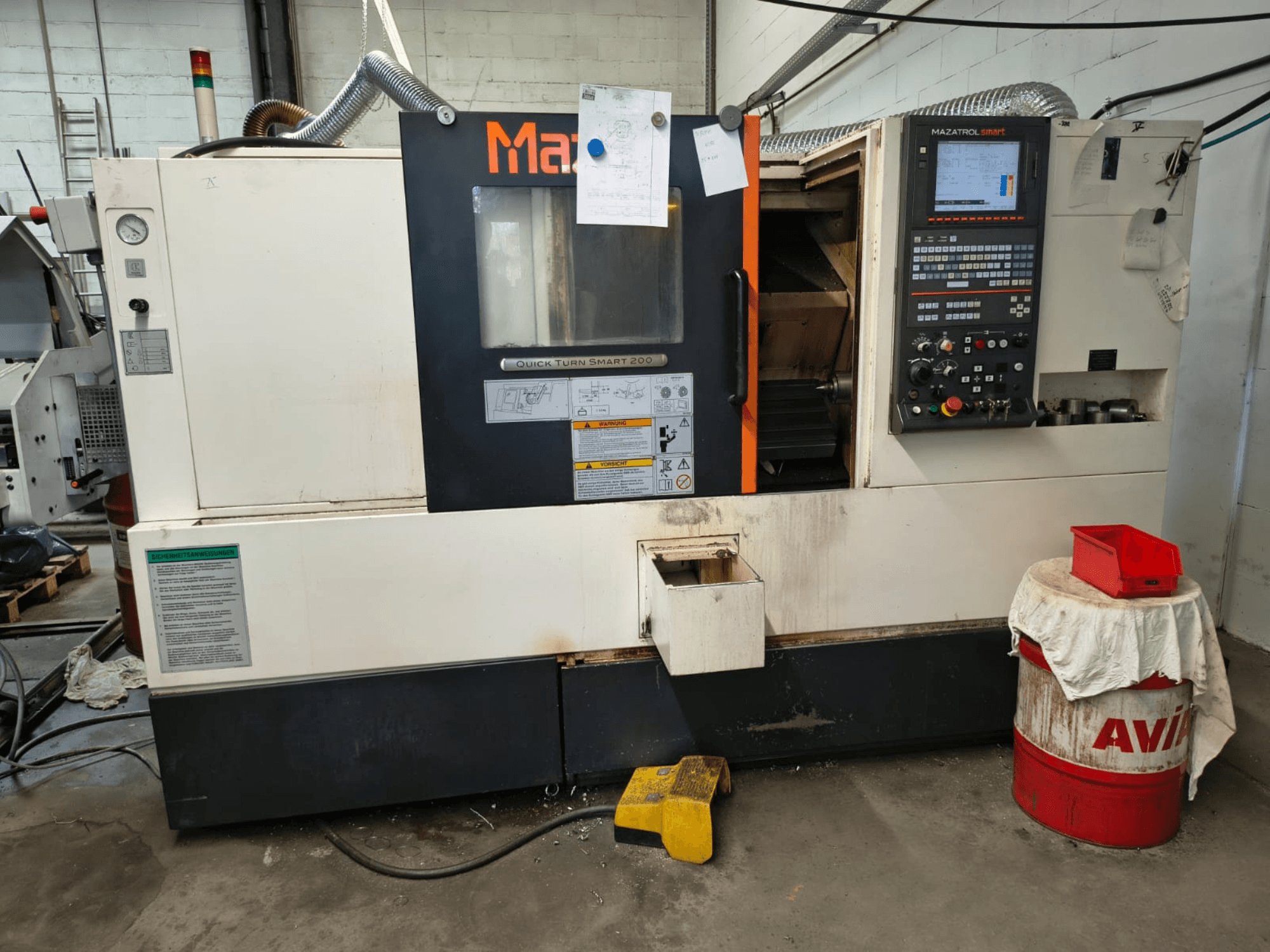 Mazak Quick Turn Smart 200, torno horizontal, vista frontal en la que se aprecian el panel de control, el depósito de refrigerante y las marcas.