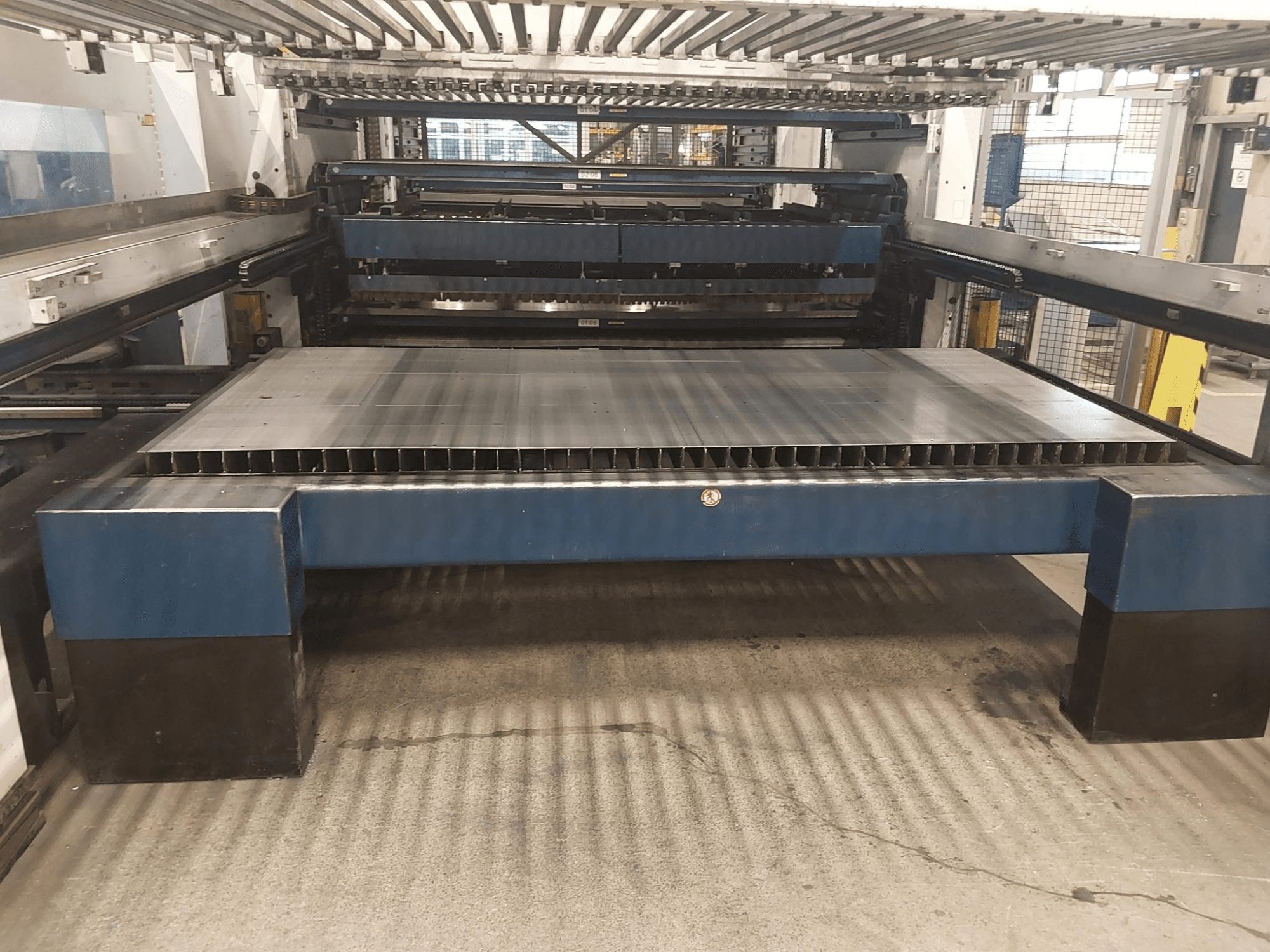 Vista frontal de la máquina de corte por láser de CO2 TRUMPF TruLaser 3030 L20 con una gran bancada de corte y estructura de soporte.