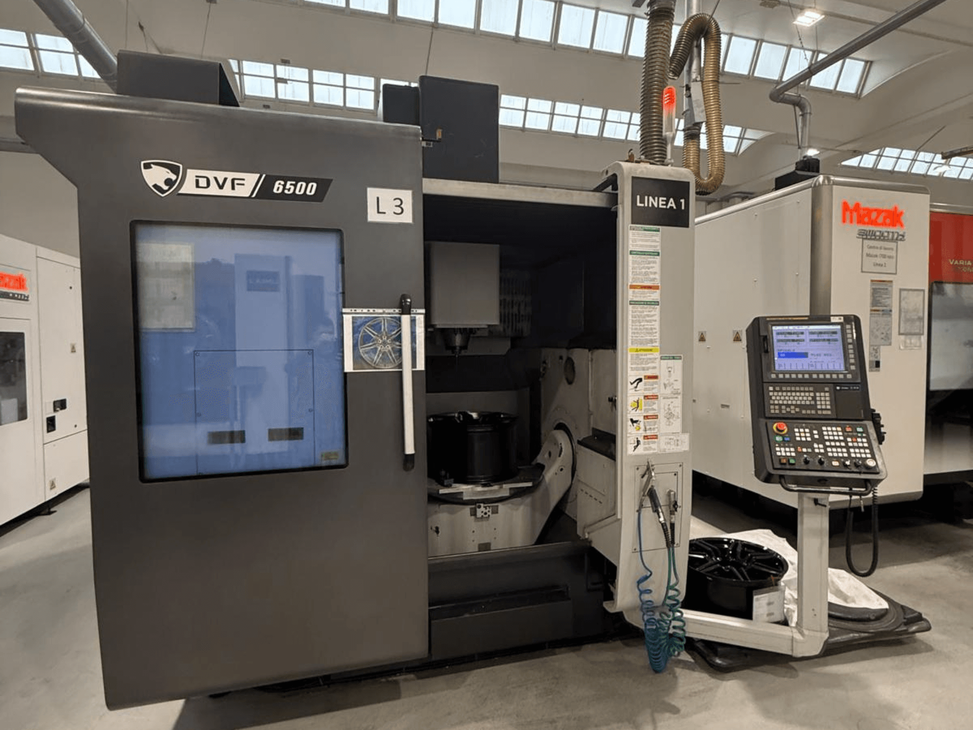 Máquina CNC DVF 6500, vista frontal, mostrando el panel de control y el espacio interior con una fijación de pieza.