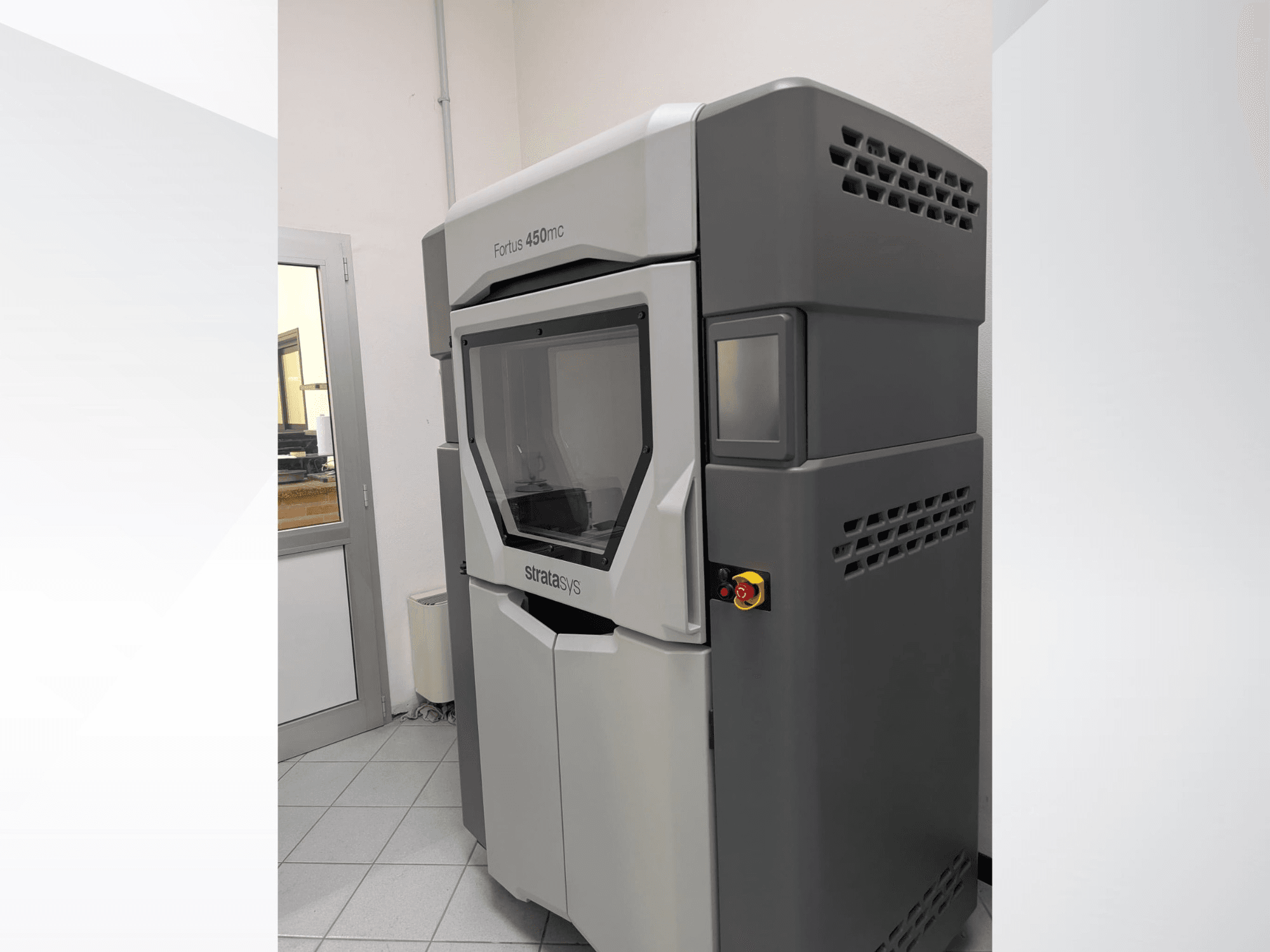 Impresora 3D de plástico Stratasys FORTUS 450mc en una vista lateral, mostrando un diseño elegante y el panel de control.
