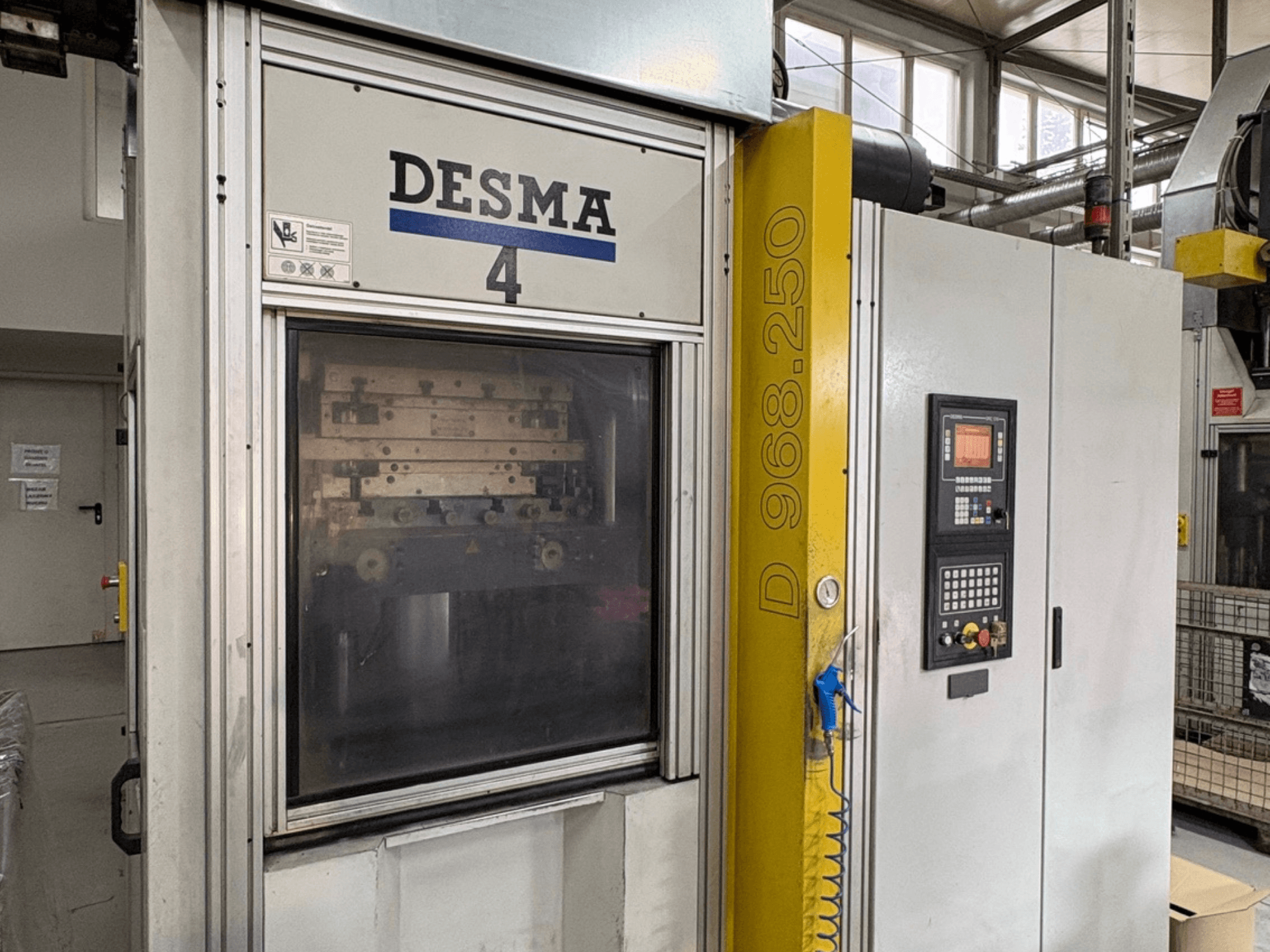 Máquina de moldeo por inyección vertical Kloeckner Desma 968.250, vista frontal con panel de control y detalles de la máquina.