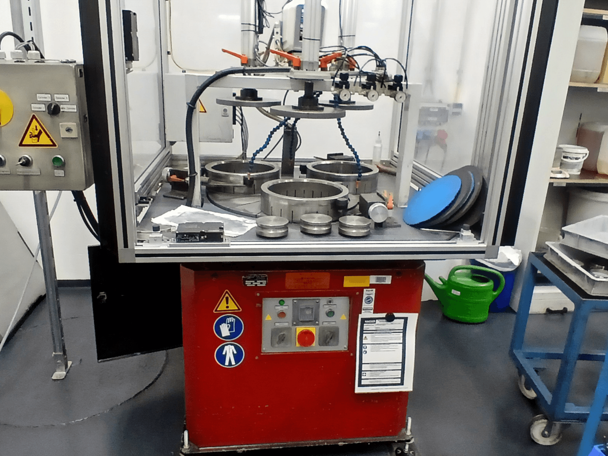 Máquina herramienta MYLÄP 700 en vista frontal, mostrando el panel de control, los componentes circulares y los dispositivos de seguridad sobre una base roja.