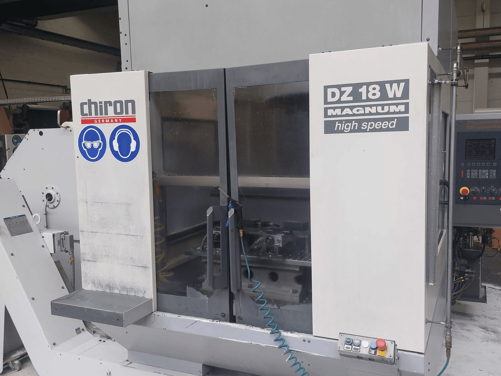 Centro de mecanizado vertical CHIRON DZ 18 W MAGNUM; vista frontal en la que se aprecian el panel de control y los gráficos de seguridad.
