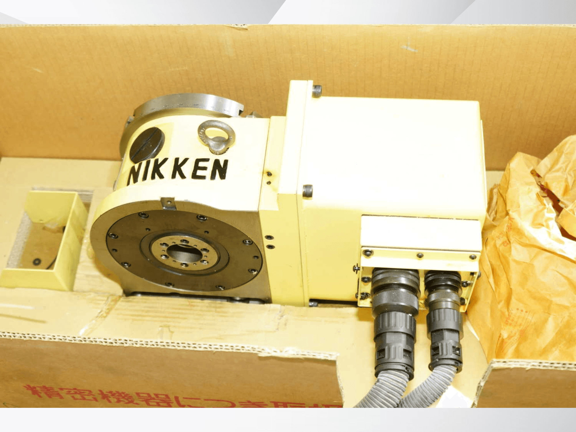 Mesa giratoria NIKKEN de color amarillo con conectores, vista frontal, en la que se muestran los componentes de mecanizado para operaciones de precisión.