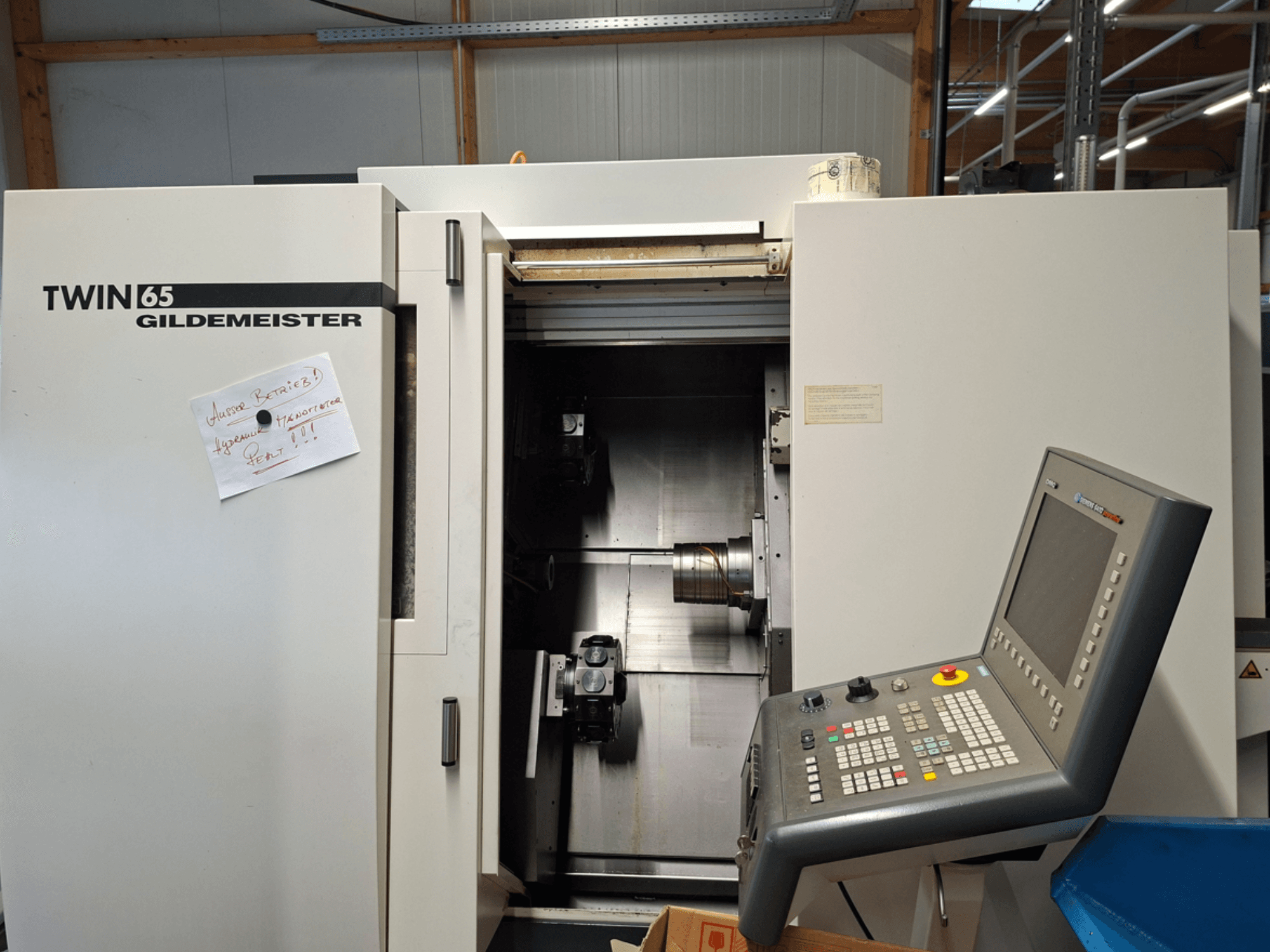 Torno CNC Gildemeister TWIN 65, vista frontal que muestra el panel de control y la cámara parcialmente abierta con la maquinaria visible.