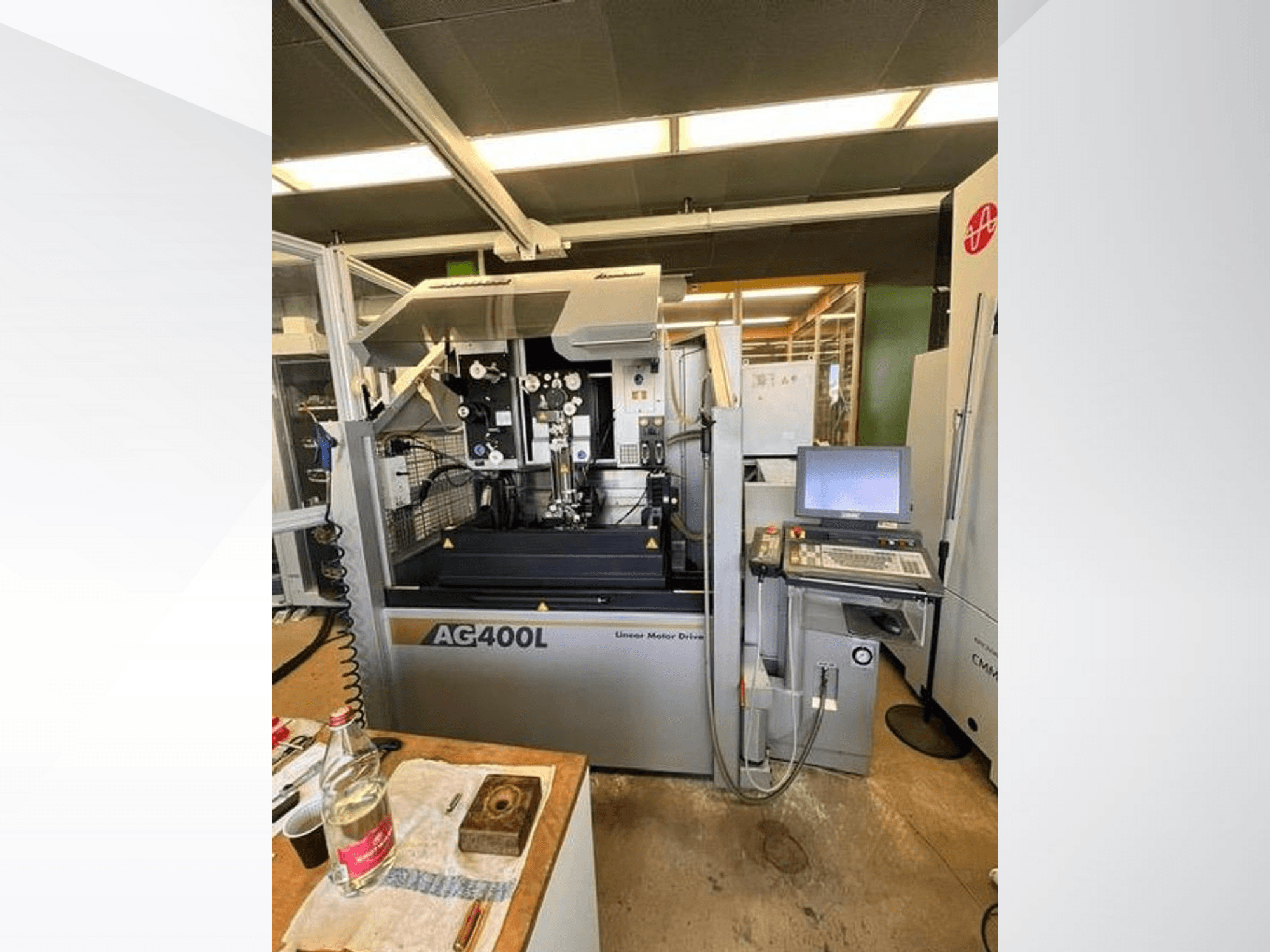 Máquina de accionamiento por motor lineal AG400L, vista frontal, con panel de control y zona de trabajo con elementos de seguridad visibles.