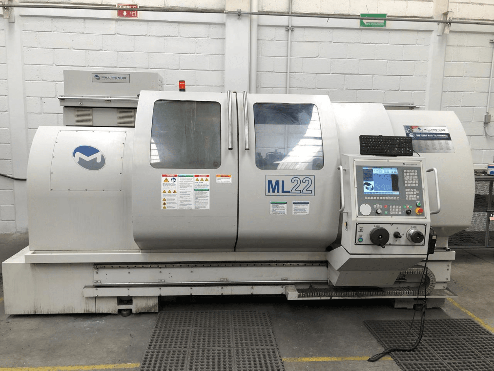 Centro de mecanizado vertical MILLTRONICS RH 20, vista frontal que muestra el panel de control, el logotipo de la marca y las etiquetas de seguridad de la máquina.